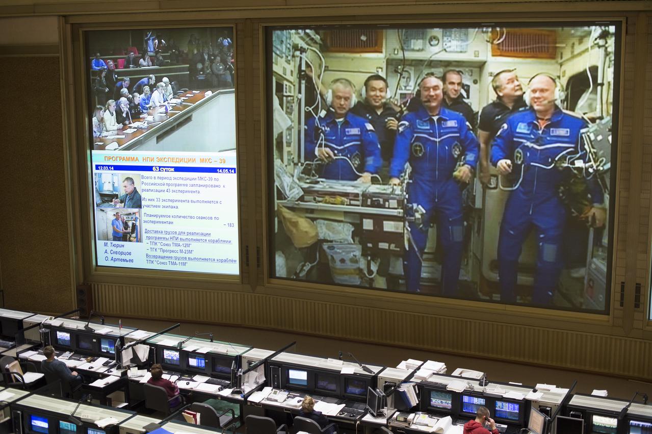 A view from the balcony of the Russian Mission Control Center shows live television of the Expedition 39 crew members gathered together on the International Space Station a few hours after the Soyuz TMA-12M spacecraft docked on Friday, March 28, 2014, in Korolev, Russia. Pictured are Expedition 39 crew members Flight Engineer Steve Swanson of NASA, left, Commander Koichi Wakata of the Japan Aerospace Exploration Agency, JAXA, back left, Flight Engineer Alexander Skvortsov of the Russian Federal Space Agency, Roscosmos, front center, Flight Engineer Rick Mastracchio of NASA, back center, Flight Engineer Mikhail Tyurin of Roscosmos, back right and Flight Engineer Oleg Artemyev of Roscosmos, front right. Swanson, Skvortsov, and Oleg's arrival to the International Space Station comes two days after they launched from the Baikonur Cosmodrome in Kazakhstan.  Photo Credit (NASA/Joel Kowsky)