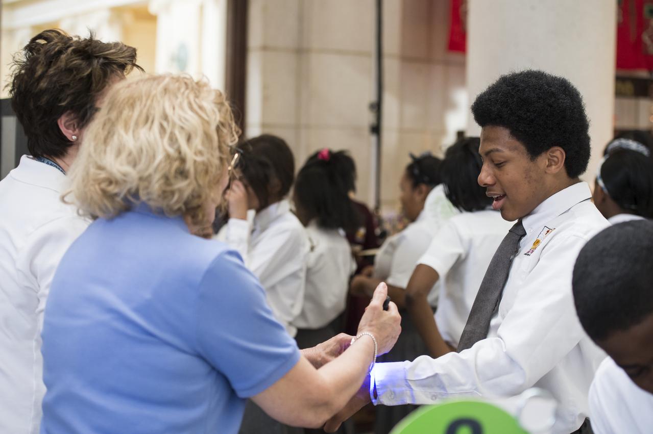 An attendee of NASA's Earth Day event observes the glow from a bracelet that is part of an exhibit at the event. The Earth Day event took place at Union Station in Washington, DC on April 22, 2014. Photo Credit: (NASA/Aubrey Gemignani)