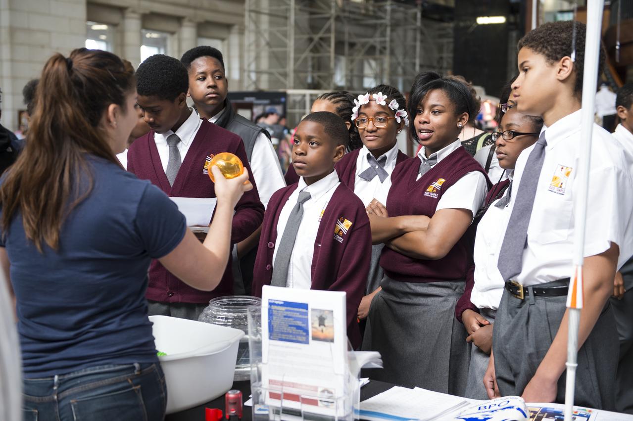 Students listen intently while an exhibitor conducts an experiment at NASA's Earth Day event. The event took place at Union Station in Washington, DC on April 22, 2014. Photo Credit: (NASA/Aubrey Gemignani)