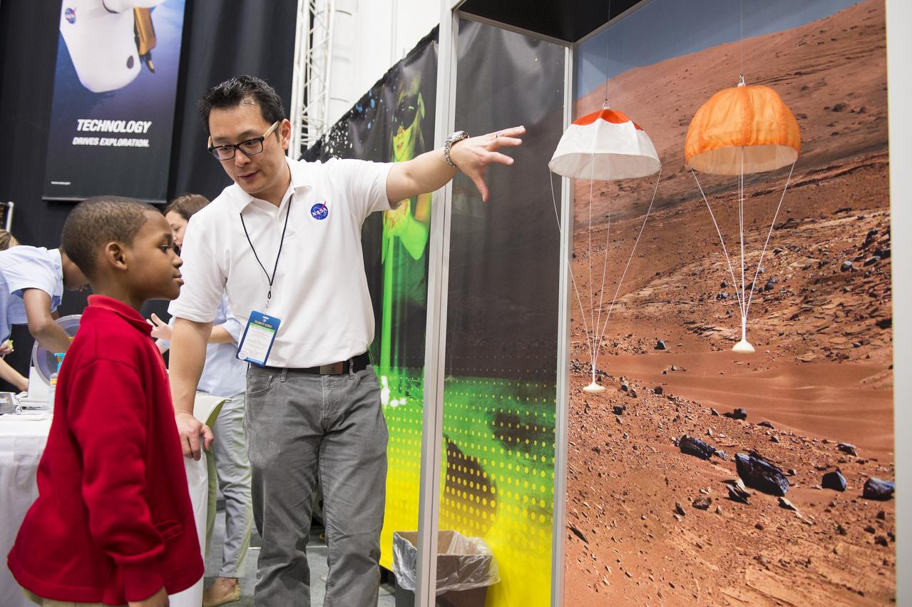 A NASA staff member describes landing technology to an attendee of the USA Science and Engineering Festival, which took place at the Washington Convention Center in Washington, DC on April 26 and 27, 2014. Photo Credit: (NASA/Aubrey Gemignani)
