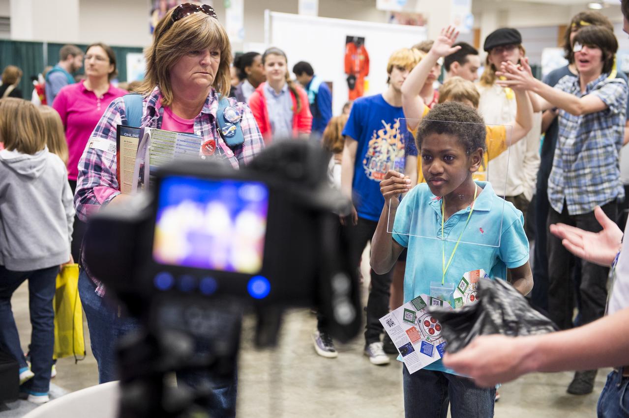 An attendee of the USA Science and Engineering Festival examines how glass blocks some heat, altering the infrared image of himself. The James Webb Space Telescope will be a large infrared telescope with a 6.5 meter primary mirror and will study every phase in the history of our Universe ranging from the Big Bang to the formation of our Solar System. The USA Science and Engineering Festival took place at the Washington Convention Center in Washington, DC on April 26 and 27, 2014. Photo Credit: (NASA/Aubrey Gemignani)