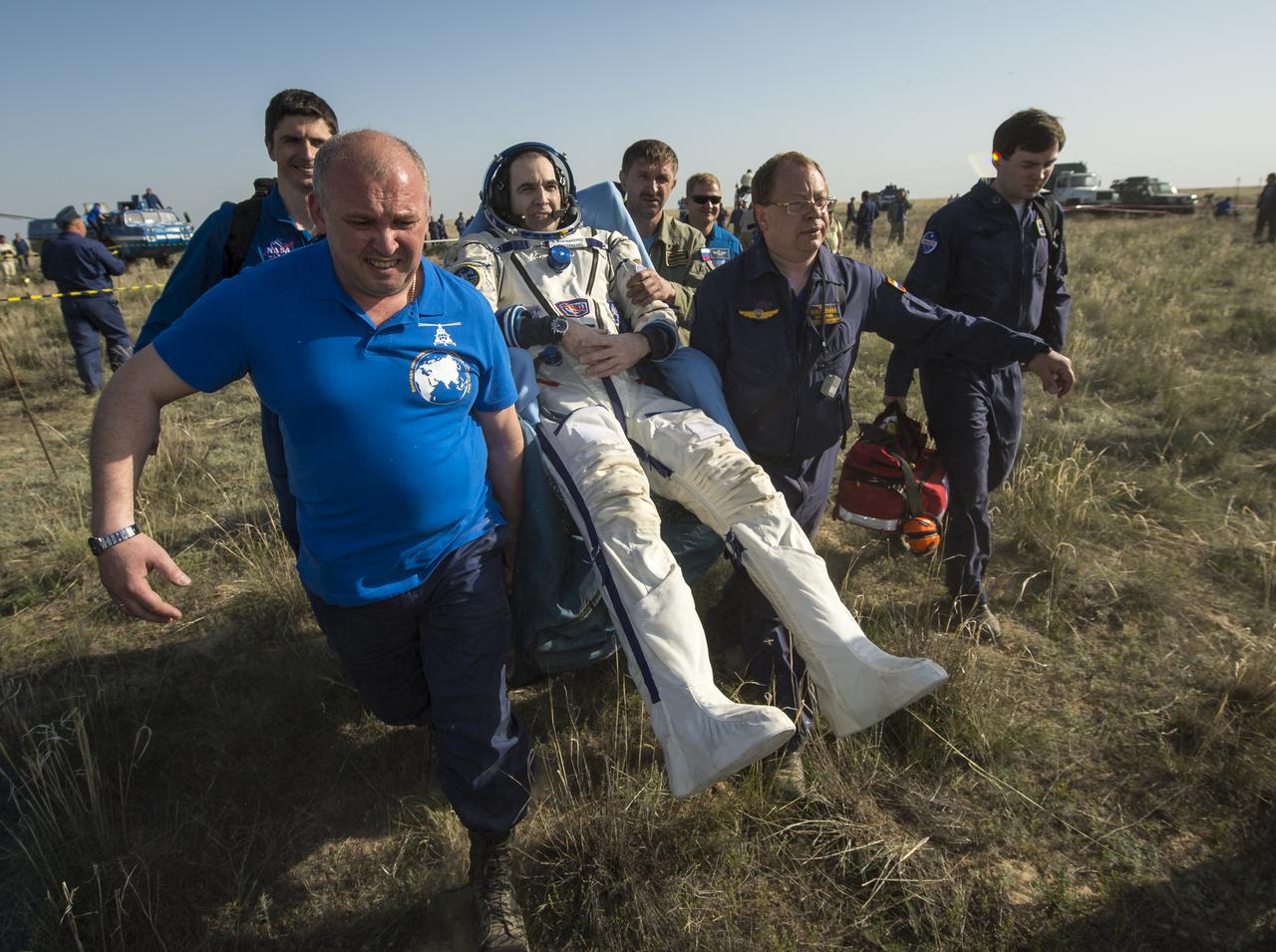 Expedition 39 Flight Engineer Rick Mastracchio of NASA is carried in a chair to a medical tent just minutes after he and Expedition 39 Commander Koichi Wakata of the Japan Aerospace Exploration Agency (JAXA), center, and Soyuz Commander Mikhail Tyurin of Roscosmos landed in their Soyuz TMA-11M spacecraft near the town of Zhezkazgan, Kazakhstan on Wednesday, May 14, 2014. Wakata, Tyurin and Mastracchio returned to Earth after more than six months onboard the International Space Station where they served as members of the Expedition 38 and 39 crews. Photo Credit: (NASA/Bill Ingalls)