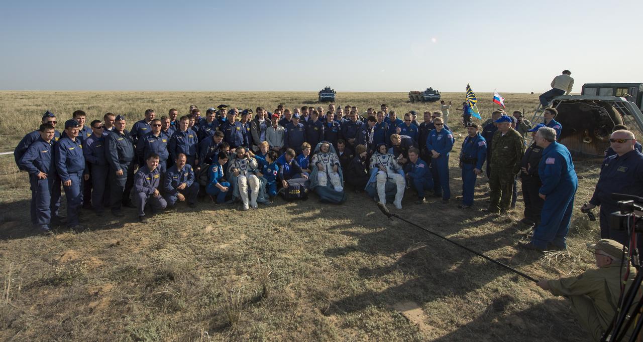Expedition 39 Commander Koichi Wakata of the Japan Aerospace Exploration Agency (JAXA), left, Soyuz Commander Mikhail Tyurin of Roscosmos, center, and Flight Engineer Rick Mastracchio of NASA, sit in chairs outside the Soyuz TMA-11M capsule and pose for a group photo with the landing team after they landed in a remote area near the town of Zhezkazgan, Kazakhstan on Wednesday, May 14, 2014. Wakata, Tyurin and Mastracchio returned to Earth after more than six months onboard the International Space Station where they served as members of the Expedition 38 and 39 crews. Photo Credit: (NASA/Bill Ingalls)