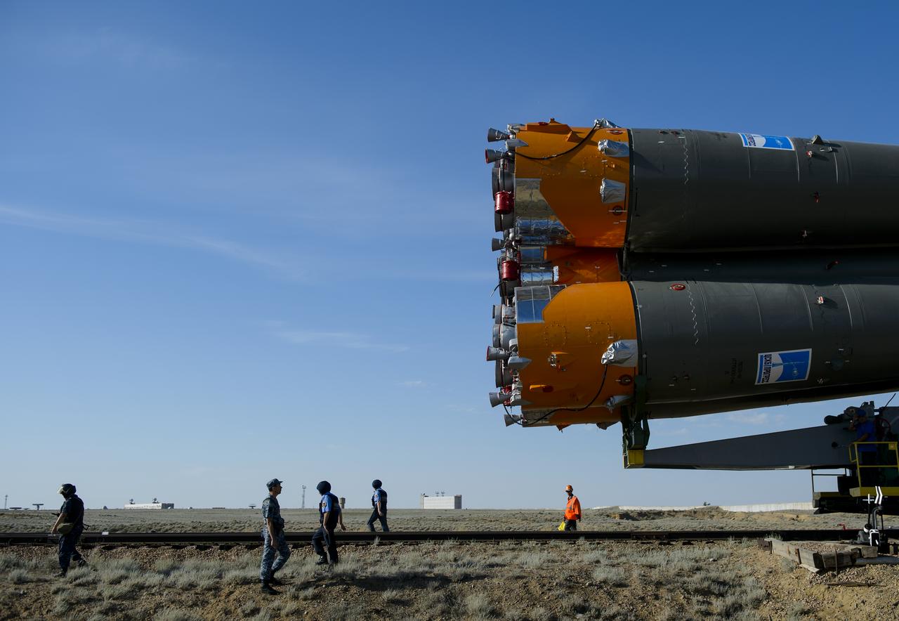 Security personnel walk in front of the Soyuz TMA-13M spacecraft as the vehicle is rolled out to the launch pad by train on Monday, May 26, 2014, at the Baikonur Cosmodrome in Kazakhstan.  Launch of the Soyuz rocket is scheduled for May 29 and will send Expedition 40 Soyuz Commander Maxim Suraev, of the Russian Federal Space Agency, Roscosmos, Flight Engineer Alexander Gerst, of the European Space Agency, ESA, and Flight Engineer Reid Wiseman of NASA on a five and a half month mission aboard the International Space Station.  Photo Credit: (NASA/Joel Kowsky)