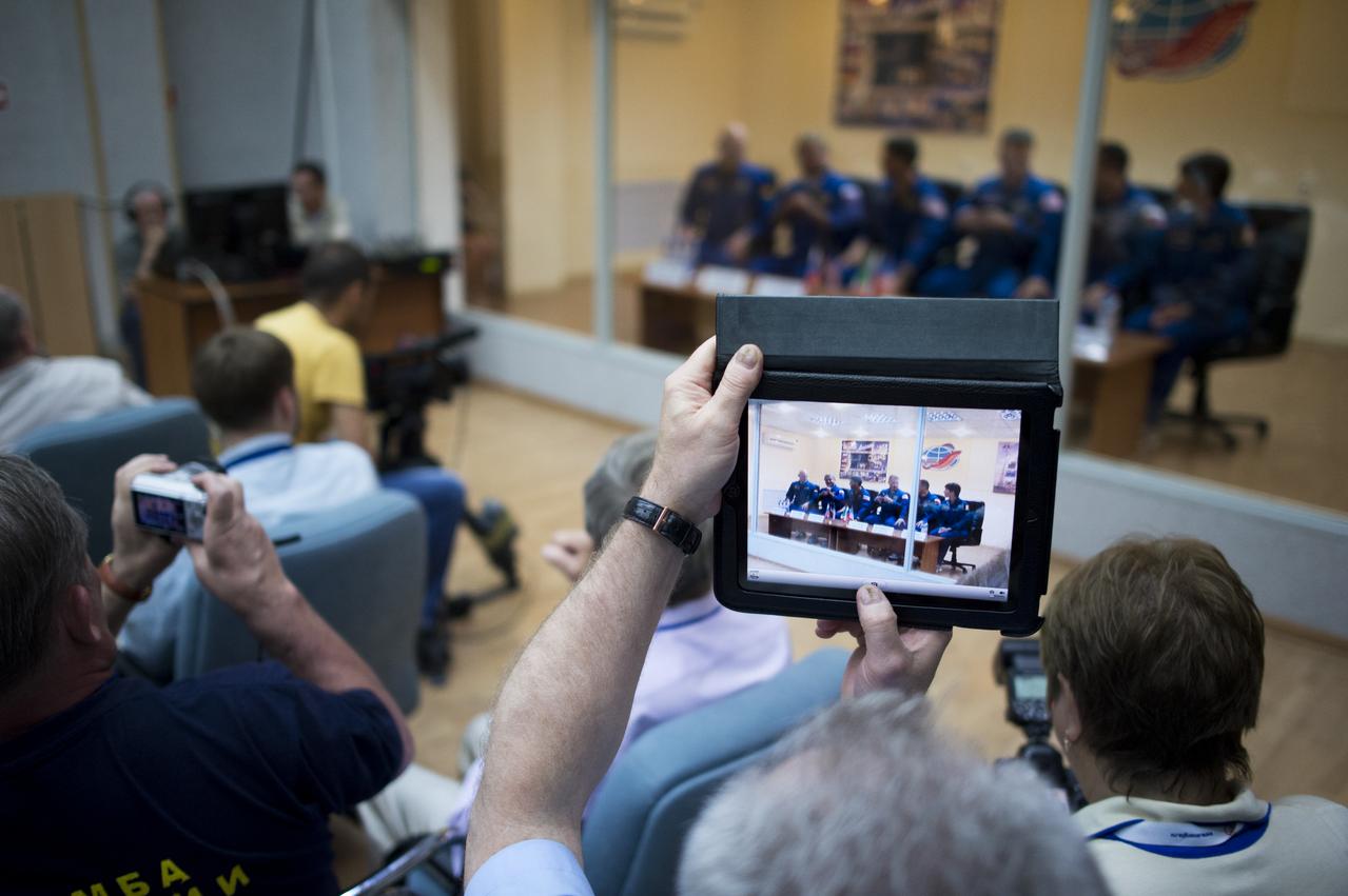 A guest takes a photo of the Expedition 40 prime and backup crews, as they sit behind glass, while in quarantine, during the State Commission meeting held to approve the Soyuz launch of the crew for a five and a half month mission aboard the International Space Station, Tuesday, May 27, 2014 at the Cosmonaut Hotel in Baikonur, Kazakhstan. Photo Credit: (NASA/Joel Kowsky)