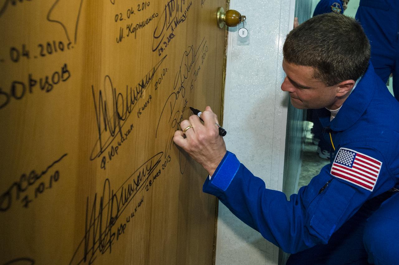 Expedition 40 Flight Engineer Reid Wiseman of NASA, performs the traditional door signing at the Cosmonaut Hotel prior to departing the hotel for launch in a Soyuz rocket with fellow crew mates, Soyuz Commander Maxim Suraev of the Russian Federal Space Agency, Roscosmos, and Flight Engineer Alexander Gerst of the European Space Agency, ESA, Wednesday, May 28, 2014, in Baikonur, Kazakhstan. Wiseman, Suraev, and Gerst will launch in their Soyuz TMA-13M spacecraft to the International Space Station to begin a five and a half month mission. Photo Credit (NASA/Joel Kowsky)