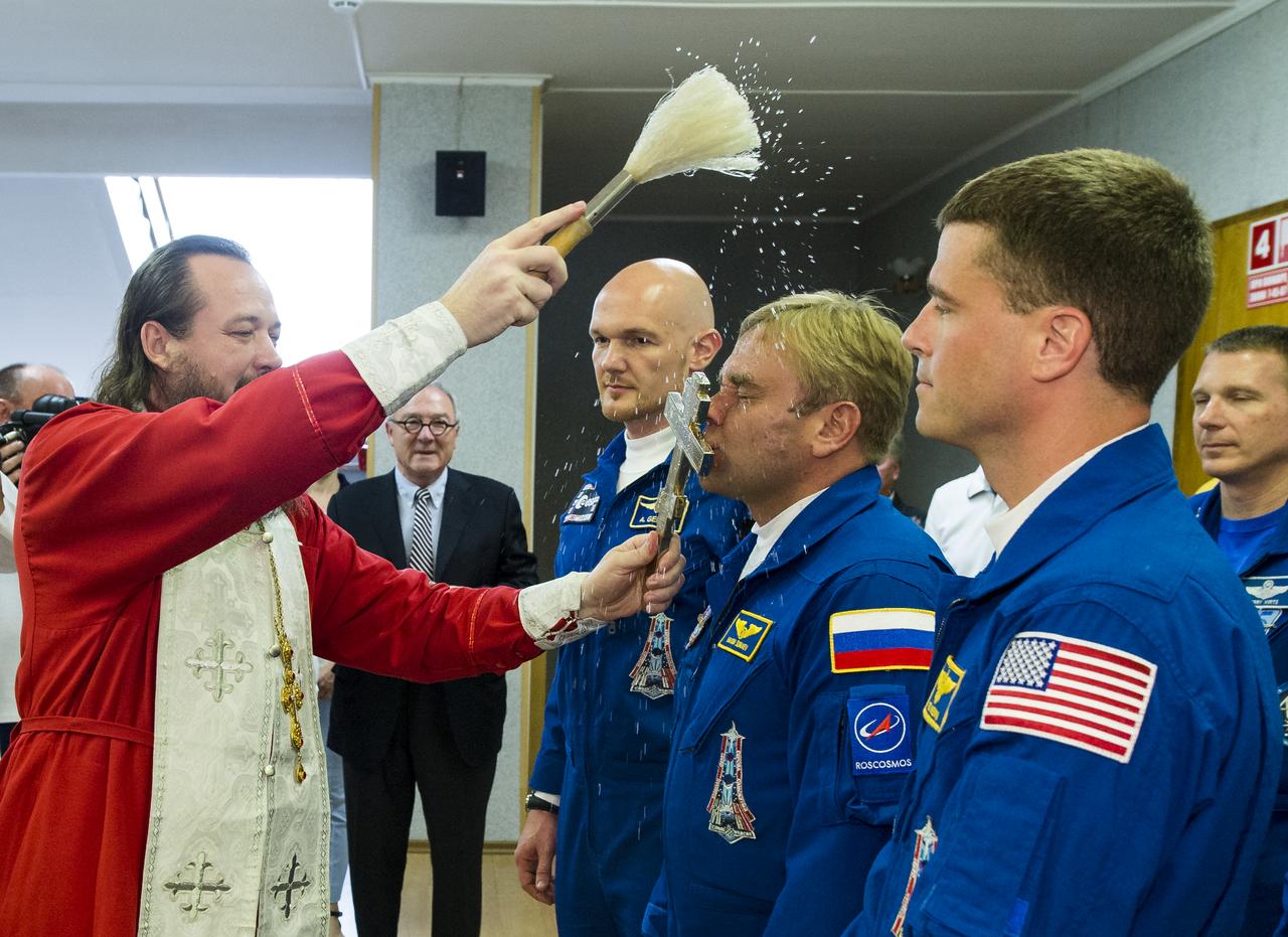 Expedition 40 Soyuz Commander Maxim Suraev of the Russian Federal Space Agency, Roscosmos, center, receives the traditional blessing from a Russian Orthodox priest at the Cosmonaut Hotel prior to his launch on the Soyuz rocket to the International Space Station, Wednesday, May 28, 2014, in Baikonur, Kazakhstan. Suraev, Flight Engineer Alexander Gerst of the European Space Agency, ESA, left, and Flight Engineer Reid Wiseman of NASA, right, will spend the next five and a half months living and working aboard the ISS. Photo Credit: (NASA/Joel Kowsky)