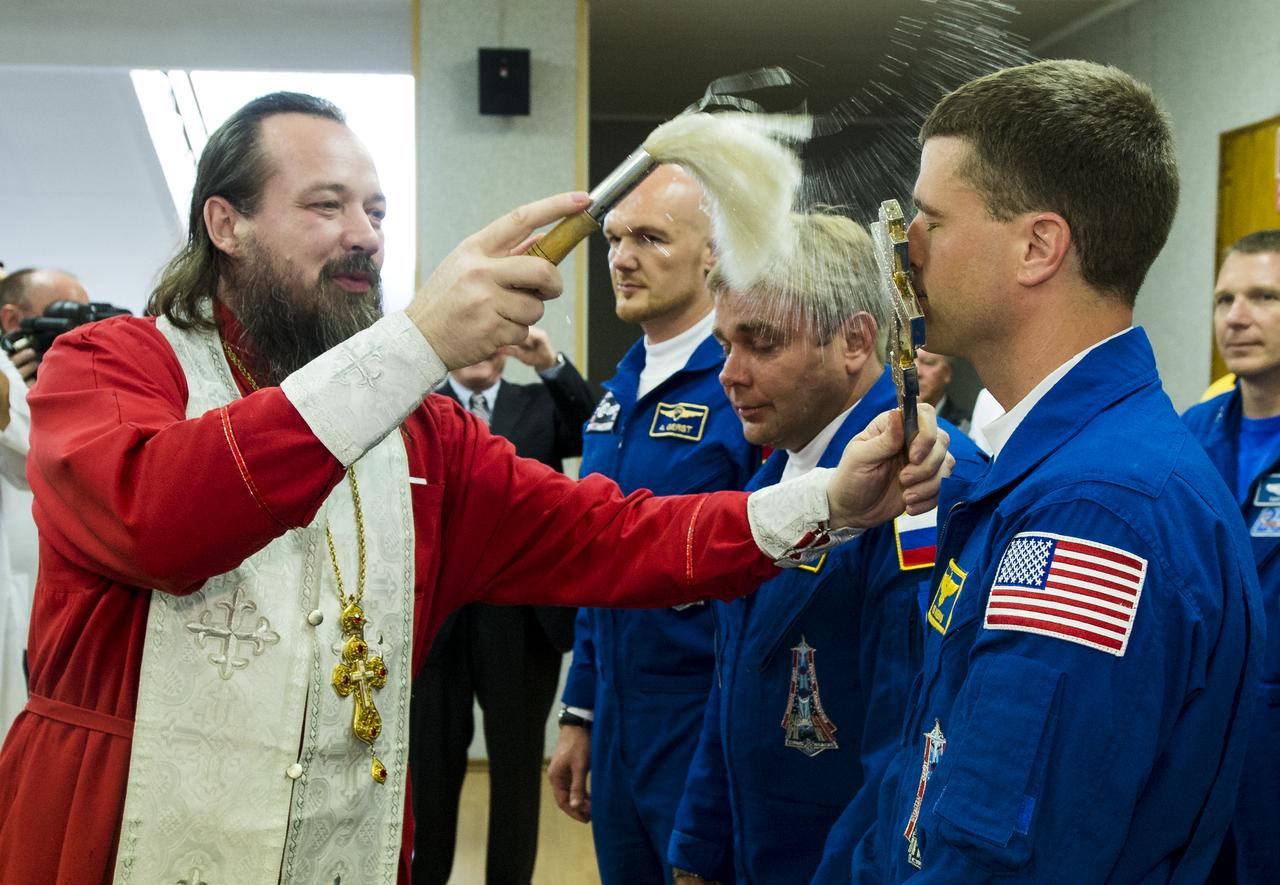 Expedition 40 Flight Engineer Reid Wiseman of NASA, right, receives the traditional blessing from a Russian Orthodox priest at the Cosmonaut Hotel prior to his launch on the Soyuz rocket to the International Space Station, Wednesday, May 28, 2014, in Baikonur, Kazakhstan. Wiseman, Soyuz Commander Maxim Suraev of the Russian Federal Space Agency, Roscosmos, center, and Flight Engineer Alexander Gerst of the European Space Agency, ESA, left, will spend the next five and a half months living and working aboard the ISS. Photo Credit: (NASA/Joel Kowsky)