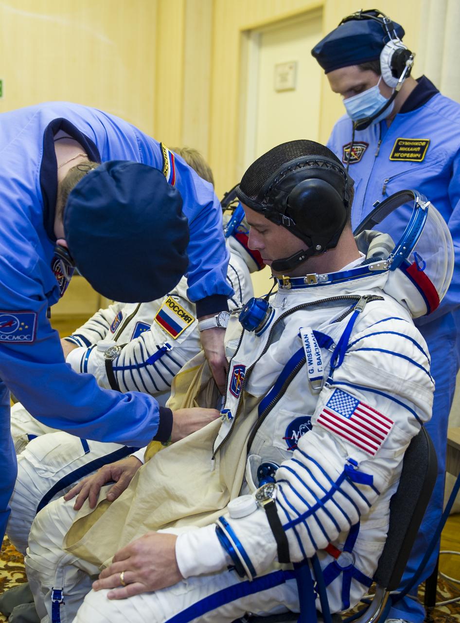 Expedition 40 Flight Engineer Reid Wiseman of NASA is helped into his Russian Sokol suit as he and fellow cremates, Soyuz Commander Maxim Suraev of the Russian Federal Space Agency, Roscosmos, and Flight Engineer Alexander Gerst of the European Space Agency, ESA, prepare for their Soyuz launch to the International Space Station, on Wednesday, May 28, 2014, in Baikonur, Kazakhstan. Launch of the Soyuz rocket will send Wiseman, Suraev, and Gerst on a five and a half month mission aboard the International Space Station. Photo Credit: (NASA/GCTC/Irina Peshkova)
