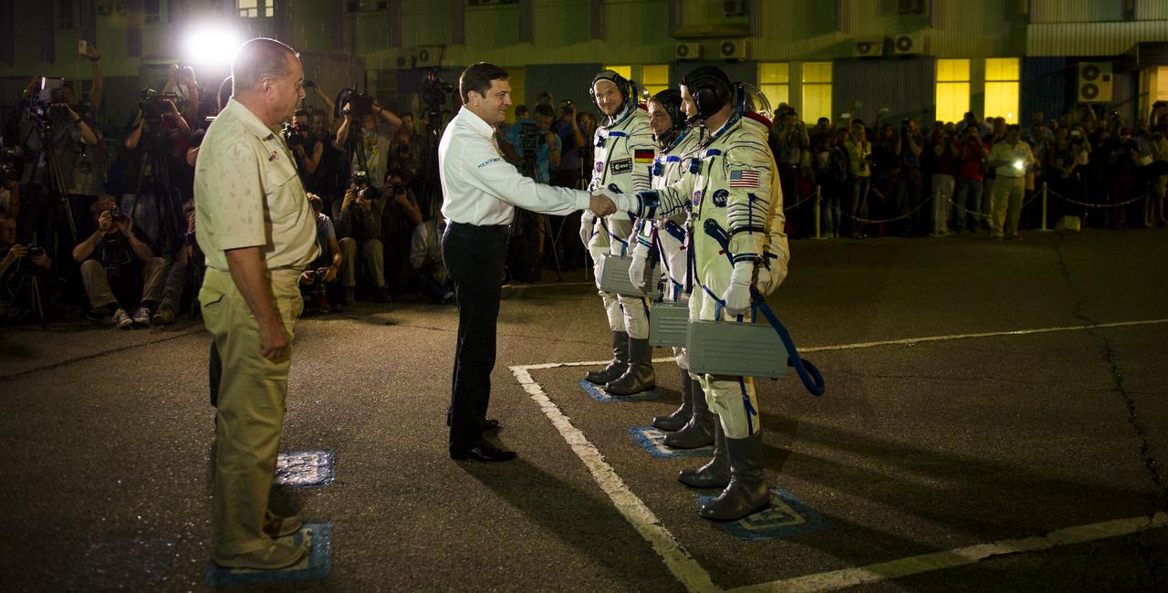 Oleg Ostapenko, General Director of the Russian Federal Space Agency, Roscosmos, center, shakes hands with Expedition 40 Flight Engineer Reid Wiseman of NASA, right, as he and crewmates Soyuz Commander Maxim Suraev of Roscosmos, and Flight Engineer Alexander Gerst of the European Space Agency, ESA, prepare to depart for the launch pad on Wednesday, May 28, 2014, in Baikonur, Kazakhstan. Launch of the Soyuz rocket will send Gerst, Suraev, and Wiseman on a five and a half month mission aboard the International Space Station. Photo Credit: (NASA/GCTC/Irina Peshkova)