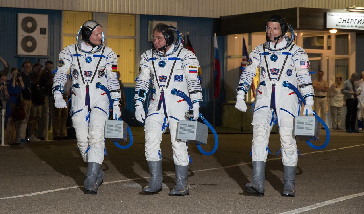 Expedition 40 Flight Engineer Alexander Gerst of the European Space Agency, ESA, left, Soyuz Commander Maxim Suraev of the Russian Federal Space Agency, Roscosmos, center, and Flight Engineer Reid Wiseman of NASA, right, are seen as they depart the Building 254 following suitup on Wednesday, May 28, 2014 in Baikonur, Kazakhstan. The trio is set to launch on a five and a half month mission to the International Space Station onboard the Soyuz TMA-13M spacecraft at 1:57 a.m. Kazakhstan time on Thursday, May 29. Photo Credit: (NASA/Victor Zelentsov)