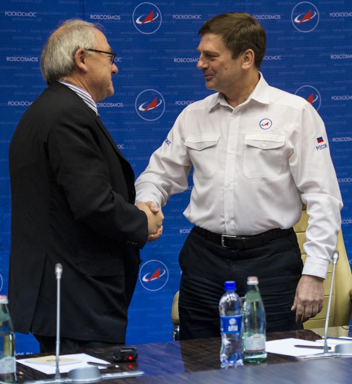 Jean-Jacques Dordain, Director General of the European Space Agency, left, and Oleg Ostapenko, General Director of the Russian Federal Space Agency, Roscosmos, right, shake hands following a joint statement after the docking of the Soyuz TMA-13M spacecraft with the International Space Station on Thursday, May 29, 2014 at the Baikonur Hotel in Baikonur, Kazakhstan.  Photo Credit: (NASA/Joel Kowsky)