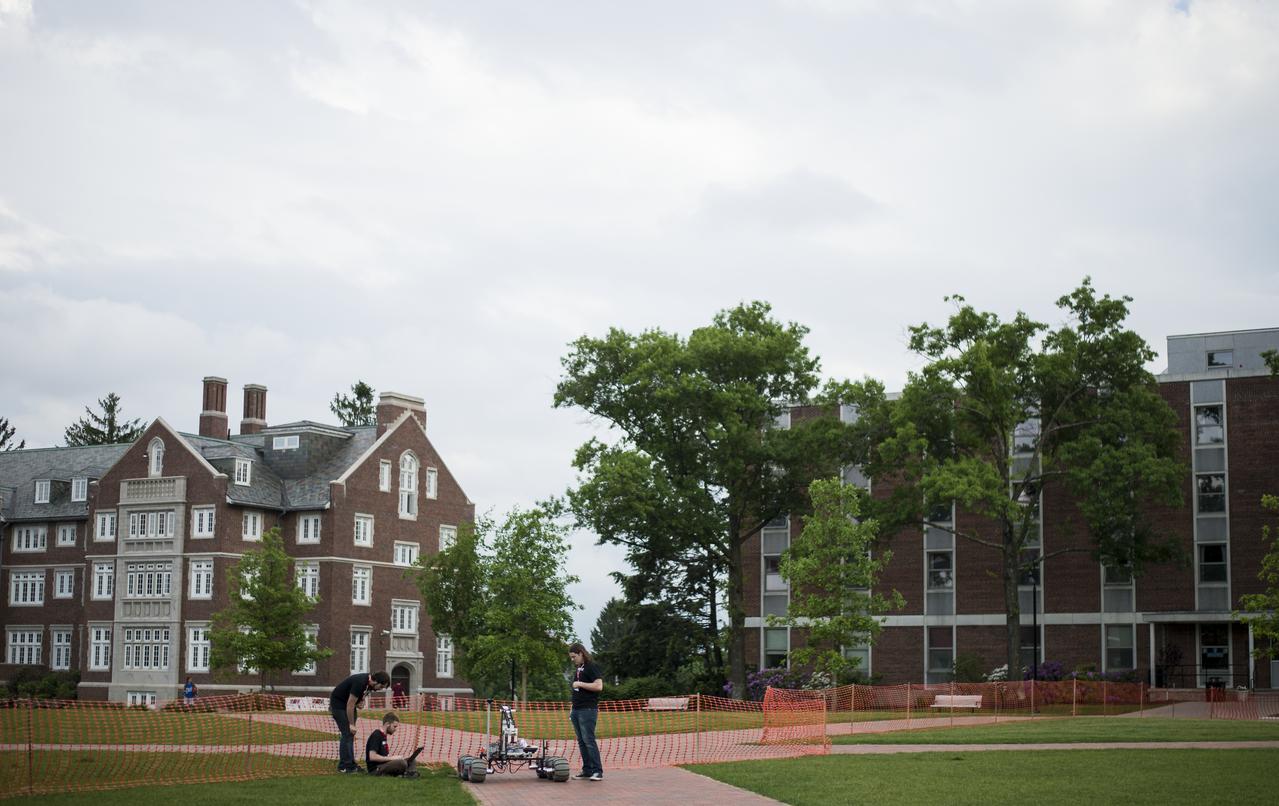 The Oregon State University Mars Rover Team follows their robot on the practice field during the 2014 NASA Centennial Challenges Sample Return Robot Challenge, Tuesday, June 10, 2014, at the Worcester Polytechnic Institute (WPI) in Worcester, Mass.   The Oregon State University Mars Rover Team is one of eighteen teams competing for a $1.5 million NASA prize purse. Teams will be required to demonstrate autonomous robots that can locate and collect samples from a wide and varied terrain, operating without human control. The objective of this NASA-WPI Centennial Challenge is to encourage innovations in autonomous navigation and robotics technologies. Innovations stemming from the challenge may improve NASA's capability to explore a variety of destinations in space, as well as enhance the nation's robotic technology for use in industries and applications on Earth. Photo Credit: (NASA/Joel Kowsky)