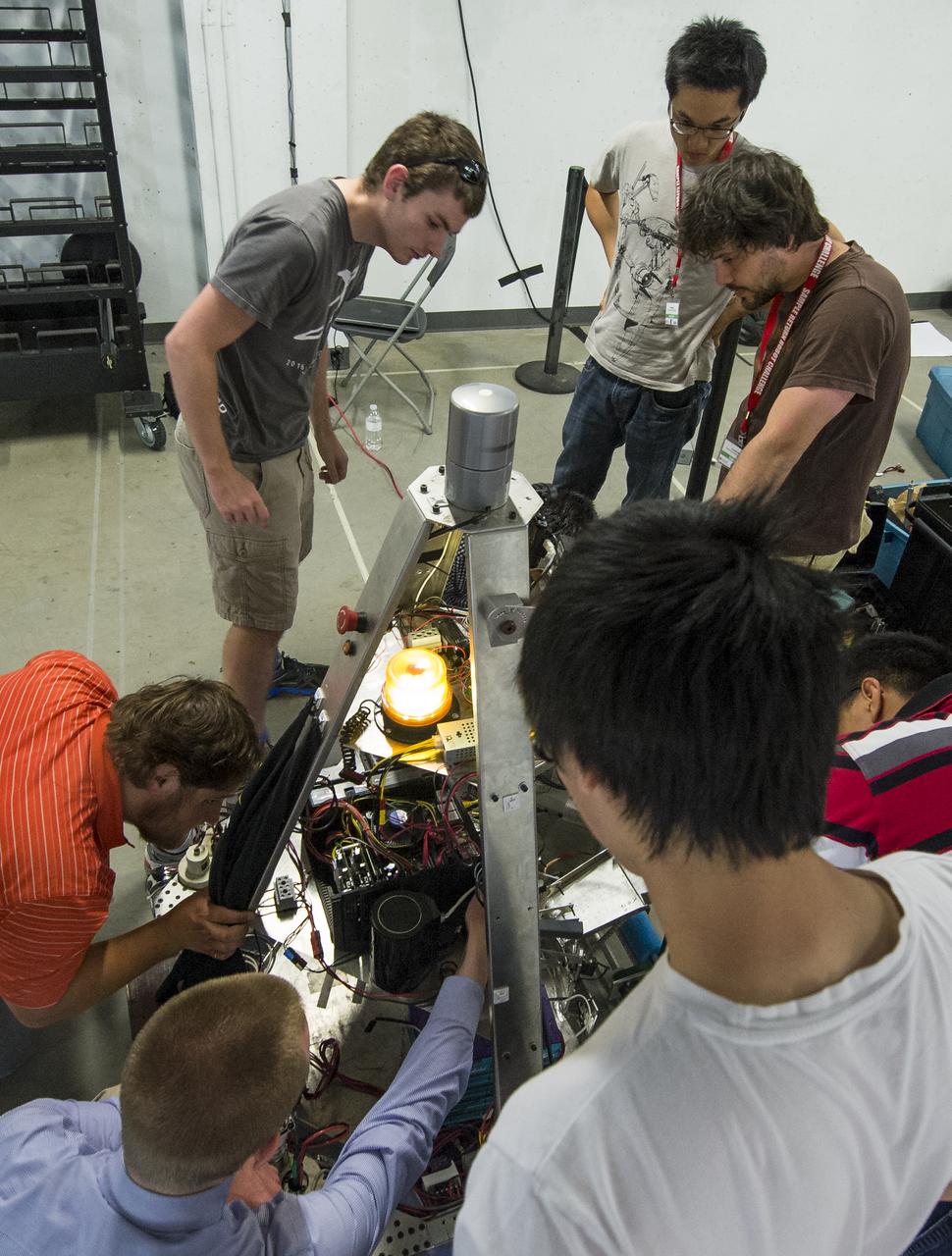 The University of Waterloo Robotics Team, from Ontario, Canada, prepares their robot for the 2014 NASA Centennial Challenges Sample Return Robot Challenge, Tuesday, June 10, 2014, at the Worcester Polytechnic Institute (WPI) in Worcester, Mass.   The team from the University of Waterloo is one of eighteen teams competing for a $1.5 million NASA prize purse. Teams will be required to demonstrate autonomous robots that can locate and collect samples from a wide and varied terrain, operating without human control. The objective of this NASA-WPI Centennial Challenge is to encourage innovations in autonomous navigation and robotics technologies. Innovations stemming from the challenge may improve NASA's capability to explore a variety of destinations in space, as well as enhance the nation's robotic technology for use in industries and applications on Earth. Photo Credit: (NASA/Joel Kowsky)
