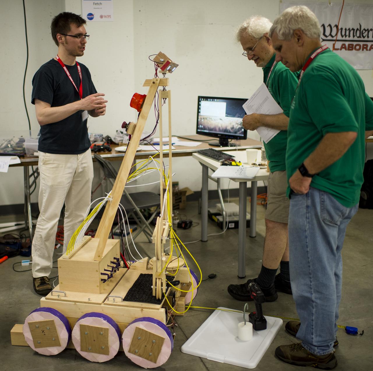 James Leopore, of team Fetch, from Alexandria, Virginia,  speaks with judges as he prepares for the NASA 2014 Sample Return Robot Challenge, Tuesday, June 10, 2014, at the Worcester Polytechnic Institute (WPI) in Worcester, Mass.  Team Fetch is one of eighteen teams competing for a $1.5 million NASA prize purse. Teams will be required to demonstrate autonomous robots that can locate and collect samples from a wide and varied terrain, operating without human control. The objective of this NASA-WPI Centennial Challenge is to encourage innovations in autonomous navigation and robotics technologies. Innovations stemming from the challenge may improve NASA's capability to explore a variety of destinations in space, as well as enhance the nation's robotic technology for use in industries and applications on Earth. Photo Credit: (NASA/Joel Kowsky)