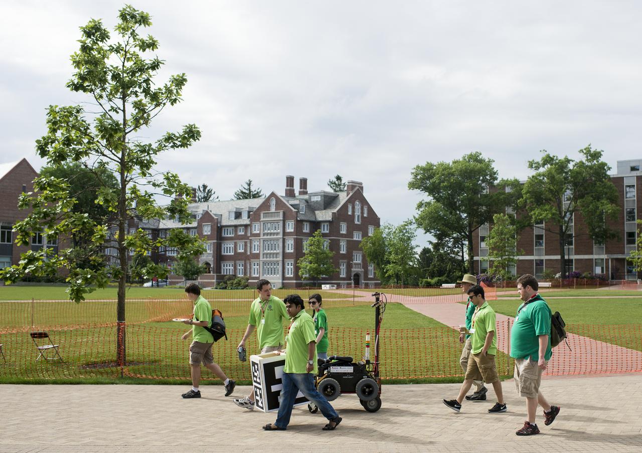 Team AERO, from the Worcester Polytechnic Institute (WPI) transports their robot to the competition field for the level one of the competition during the 2014 NASA Centennial Challenges Sample Return Robot Challenge, Wednesday, June 11, 2014, at the Worcester Polytechnic Institute (WPI) in Worcester, Mass.  Eighteen teams are competing for a $1.5 million NASA prize purse. Teams will be required to demonstrate autonomous robots that can locate and collect samples from a wide and varied terrain, operating without human control. The objective of this NASA-WPI Centennial Challenge is to encourage innovations in autonomous navigation and robotics technologies. Innovations stemming from the challenge may improve NASA's capability to explore a variety of destinations in space, as well as enhance the nation's robotic technology for use in industries and applications on Earth. Photo Credit: (NASA/Joel Kowsky)