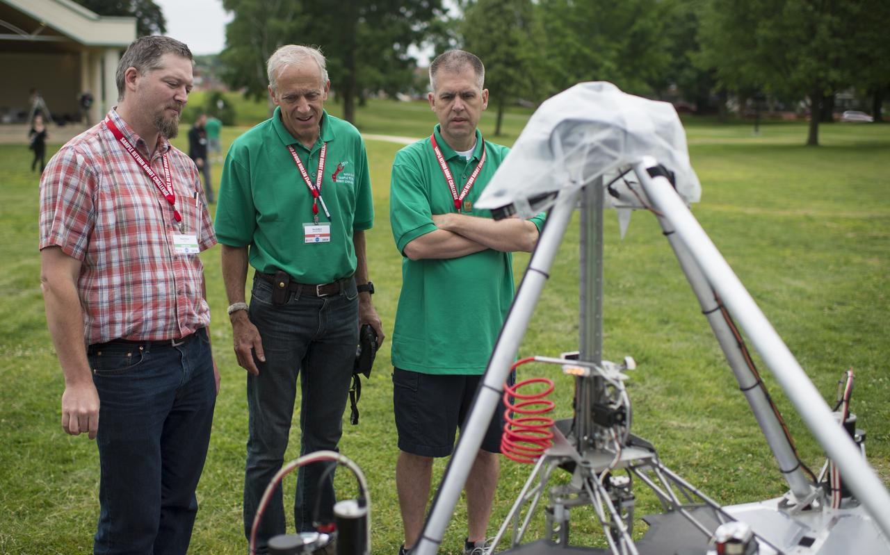 Russel Howe of team Survey speaks with Sample Return Robot Challenge staff members after the team's robot failed to leave the starting platform during it's attempt at the level two challenge during the 2014 NASA Centennial Challenges Sample Return Robot Challenge, Thursday, June 12, 2014, at the Worcester Polytechnic Institute (WPI) in Worcester, Mass.   Eighteen teams are competing for a $1.5 million NASA prize purse. Teams will be required to demonstrate autonomous robots that can locate and collect samples from a wide and varied terrain, operating without human control. The objective of this NASA-WPI Centennial Challenge is to encourage innovations in autonomous navigation and robotics technologies. Innovations stemming from the challenge may improve NASA's capability to explore a variety of destinations in space, as well as enhance the nation's robotic technology for use in industries and applications on Earth. Photo Credit: (NASA/Joel Kowsky)