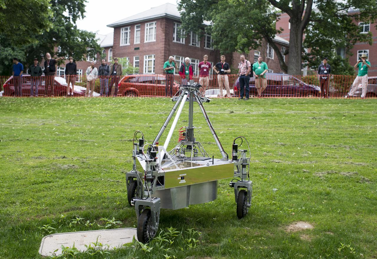 Spectators watch as the team Survey robot conducts a demonstration of the level two challenge during the 2014 NASA Centennial Challenges Sample Return Robot Challenge, Thursday, June 12, 2014, at the Worcester Polytechnic Institute (WPI) in Worcester, Mass.   Eighteen teams are competing for a $1.5 million NASA prize purse. Teams will be required to demonstrate autonomous robots that can locate and collect samples from a wide and varied terrain, operating without human control. The objective of this NASA-WPI Centennial Challenge is to encourage innovations in autonomous navigation and robotics technologies. Innovations stemming from the challenge may improve NASA's capability to explore a variety of destinations in space, as well as enhance the nation's robotic technology for use in industries and applications on Earth. Photo Credit: (NASA/Joel Kowsky)