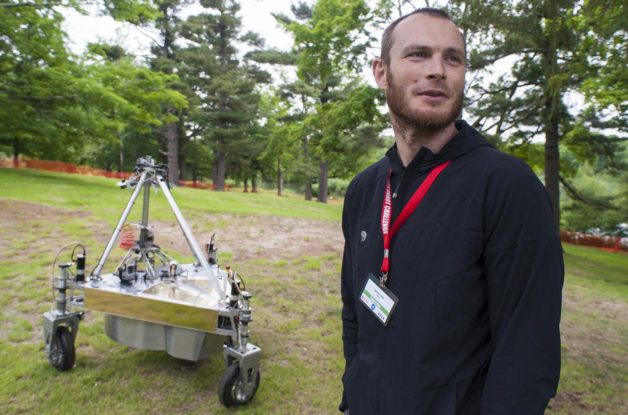 Jascha Little of team Survey is seen as he follows the teams robot as it conducts a demonstration of the level two challenge during the 2014 NASA Centennial Challenges Sample Return Robot Challenge, Thursday, June 12, 2014, at the Worcester Polytechnic Institute (WPI) in Worcester, Mass. Eighteen teams are competing for a $1.5 million NASA prize purse. Teams will be required to demonstrate autonomous robots that can locate and collect samples from a wide and varied terrain, operating without human control. The objective of this NASA-WPI Centennial Challenge is to encourage innovations in autonomous navigation and robotics technologies. Innovations stemming from the challenge may improve NASA's capability to explore a variety of destinations in space, as well as enhance the nation's robotic technology for use in industries and applications on Earth. Photo Credit: (NASA/Joel Kowsky)
