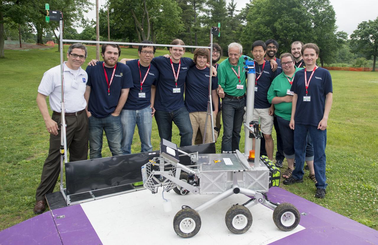 Members of team Mountaineers pose with officials from the 2014 NASA Centennial Challenges Sample Return Robot Challenge on Saturday, June 14, 2014 at Worcester Polytechnic Institute (WPI) in Worcester, Mass. Team Mountaineer was the only team to complete the level one challenge this year.  Team Mountaineer members, from left (in blue shirts) are: Ryan Watson, Marvin Cheng, Scott Harper, Jarred Strader, Lucas Behrens, Yu Gu, Tanmay Mandal, Alexander Hypes, and Nick Ohi   Challenge judges and competition staff (in white and green polo shirts) from left are: Sam Ortega, NASA Centennial Challenge program manager; Ken Stafford, challenge technical advisor, WPI; Colleen Shaver, challenge event manager, WPI. During the competition, teams were required to demonstrate autonomous robots that can locate and collect samples from a wide and varied terrain, operating without human control. The objective of this NASA-WPI Centennial Challenge was to encourage innovations in autonomous navigation and robotics technologies. Innovations stemming from the challenge may improve NASA's capability to explore a variety of destinations in space, as well as enhance the nation's robotic technology for use in industries and applications on Earth.  Photo Credit: (NASA/Joel Kowsky)