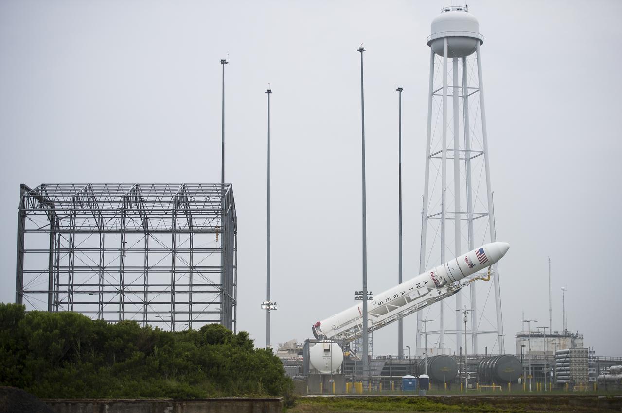 The Orbital Sciences Corporation Antares rocket, with the Cygnus spacecraft onboard, is raised at launch Pad-0A, Thursday, July 10, 2014, at NASA's Wallops Flight Facility in Virginia. The Antares will launch with the Cygnus spacecraft filled with over 3,000 pounds of supplies for the International Space Station, including science experiments, experiment hardware, spare parts, and crew provisions. The Orbital-2 mission is Orbital Sciences' second contracted cargo delivery flight to the space station for NASA. Photo Credit: (NASA/Aubrey Gemignani)