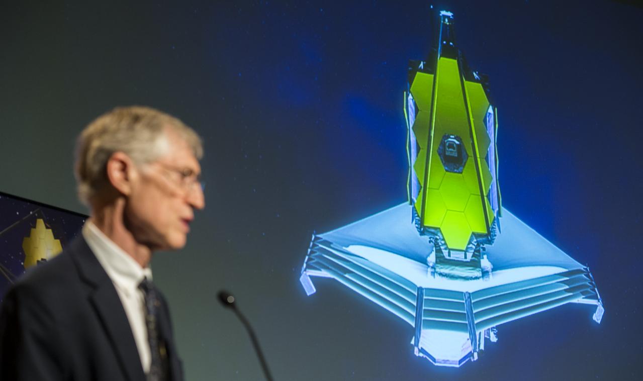 An animation of the James Webb Space Telescope (JWST) is projected as John Mather, Nobel Laureate and Project Scientist for the JWST speaks during a panel discussion on the search for life beyond Earth in the James E. Webb Auditorium at NASA Headquarters on Monday, July 14, 2014 in Washington, DC. The panel discussed how NASA's space-based observatories are making new discoveries and how the agency's new telescope, the James Webb Space Telescope, will continue this path of discovery after its schedule launch in 2018.   Photo Credit: (NASA/Joel Kowsky)