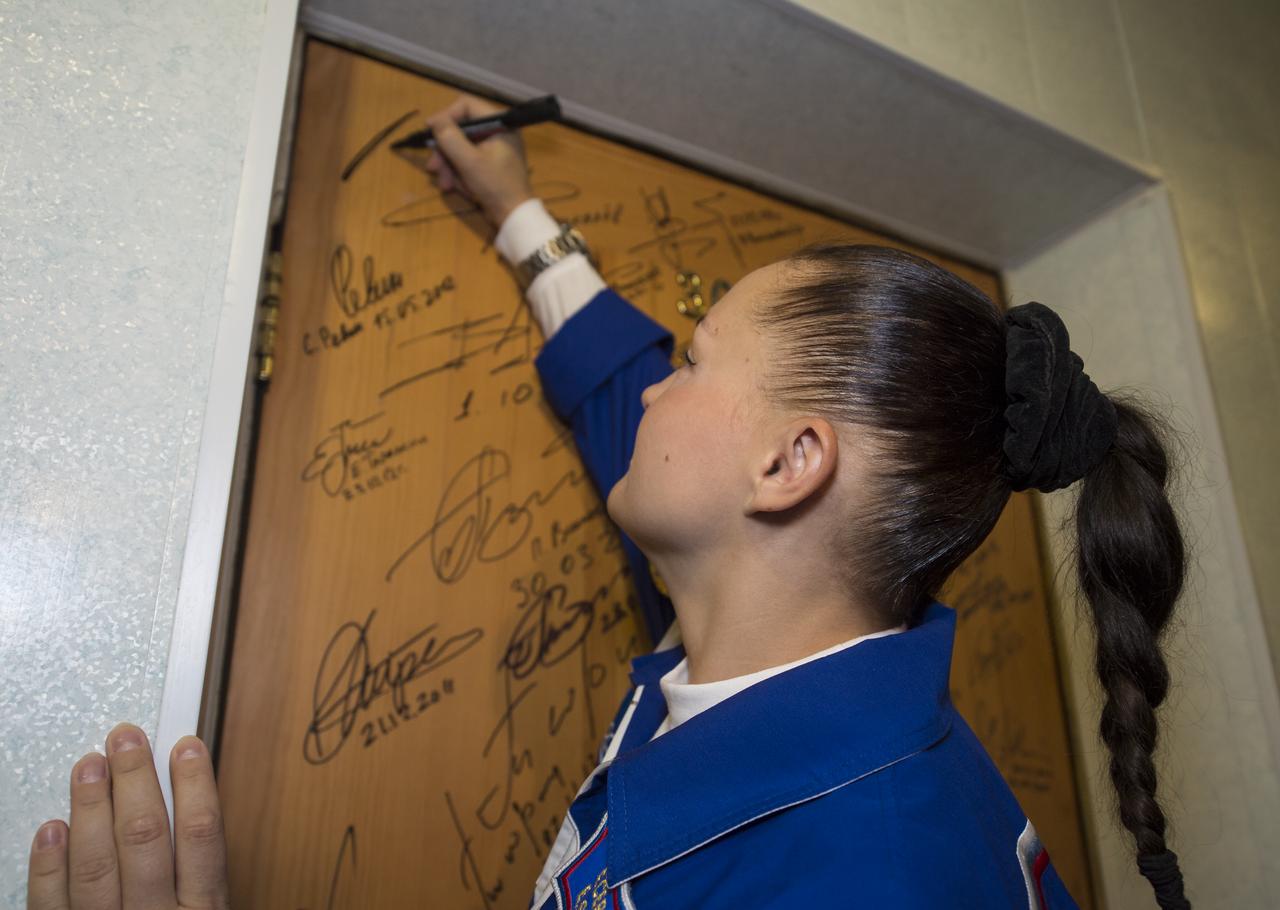 Expedition 41 Flight Engineer Elena Serova of the Russian Federal Space Agency (Roscosmos), performs the traditional door signing at the Cosmonaut Hotel prior to departing the hotel for launch in a Soyuz rocket with fellow crew mates, Soyuz Commander Alexander Samokutyaev of Roscosmos and Flight Engineer Barry Wilmore of NASA, Thursday, Sept. 25, 2014 in Baikonur, Kazakhstan. Launch of the Soyuz rocket is scheduled for the early hours of Sept. 26 Kazakhstan time and will carry Serova, Wilmore, and Samokutyaev into orbit to begin their five and a half month mission on the International Space Station. Serova will become the fourth Russian woman to fly in space and the first Russian woman to live and work on the station. Photo Credit (NASA/Aubrey Gemignani)