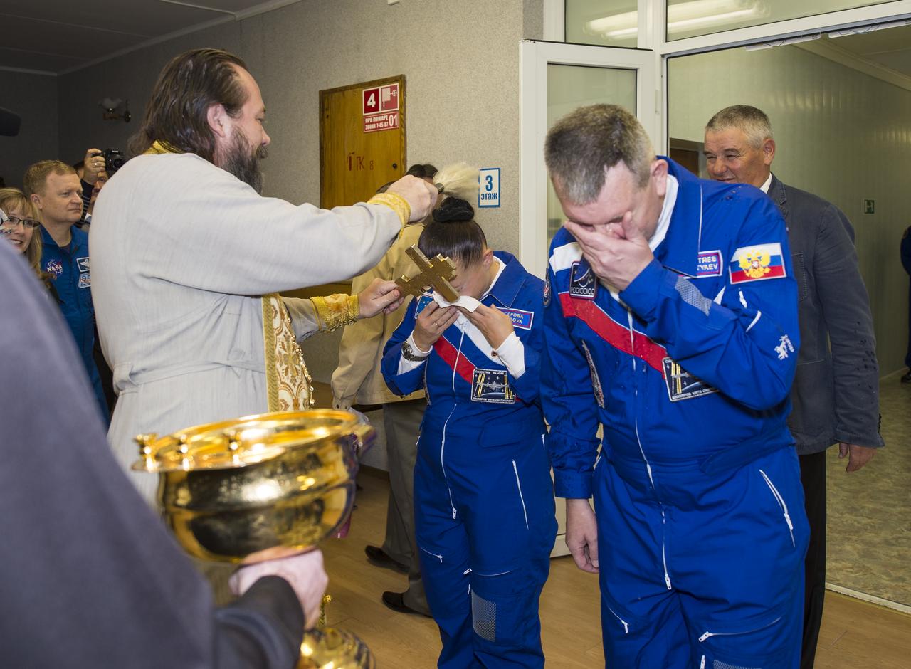 Expedition 41 Flight Engineer Elena Serova of the Russian Federal Space Agency (Roscosmos), left, receives the traditional blessing from a Russian Orthodox priest at the Cosmonaut Hotel prior to her launch on the Soyuz rocket to the International Space Station (ISS), Thursday, Sept. 25, 2014, in Baikonur, Kazakhstan. She and fellow crew mates, Soyuz Commander Alexander Samokutyaev of Roscosmos, right, and Flight Engineer Barry Wilmore of NASA, not pictured, will spend the next five and a half months living and working aboard the ISS. Wilmore chose not to participate in the blessing. Serova will become the fourth Russian woman to fly in space and the first Russian woman to live and work on the station. Photo Credit: (NASA/Aubrey Gemignani)