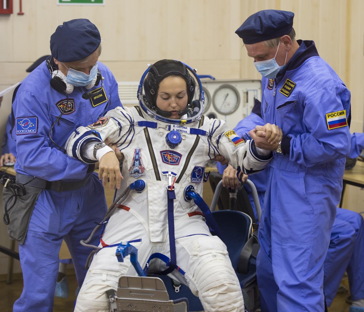Expedition 41 Flight Engineer Elena Serova of the Russian Federal Space Agency (Roscosmos) is helped up after her Russian Sokol suit was pressure checked in preparation for her launch aboard the Soyuz TMA-14M spacecraft on Thursday, Sept. 25, 2014, at the Baikonur Cosmodrome in Baikonur, Kazakhstan. Launch of the Soyuz rocket is scheduled for the early hours of Sept. 26 (Kazakhstan time) and will carry Serova and fellow crewmates, Soyuz Commander Alexander Samokutyaev of Roscosmos and Flight Engineer Barry Wilmore of NASA, into orbit to begin their five and a half month mission on the International Space Station. Serova will become the fourth Russian woman to fly in space and the first Russian woman to live and work on the station. Photo Credit: (NASA/Aubrey Gemignani)