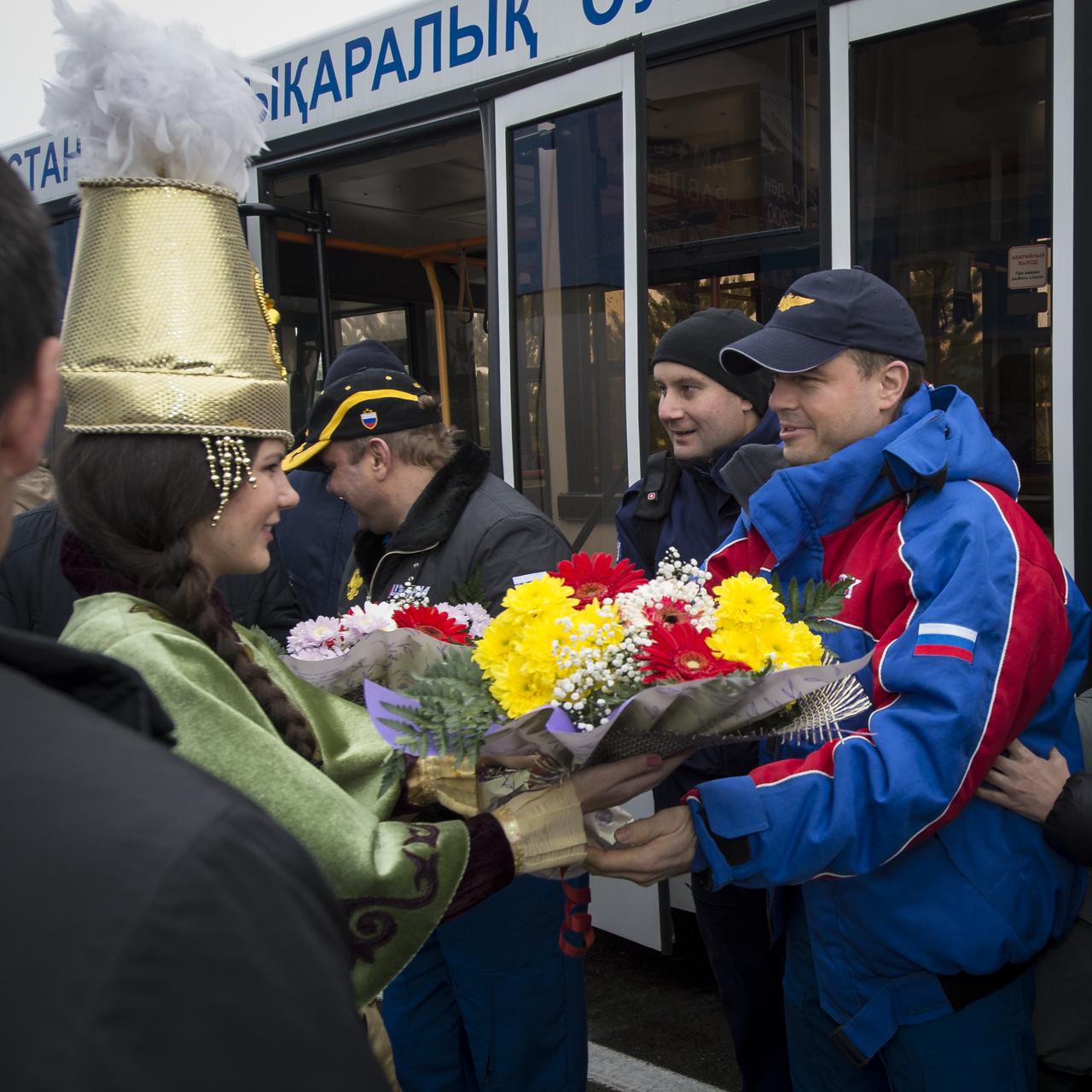 A woman in ceremonial Kazakh dress presents flowers to Expedition 41 Flight Engineer Reid Wiseman of NASA at the Kustanay Airport after he and Expedition 41 Commander Max Suraev of the Russian Federal Space Agency (Roscosmos) and Flight Engineer Alexander Gerst of the European Space Agency (ESA) landed in their Soyuz TMA-13M capsule in a remote area near the town of Arkalyk, Kazakhstan on Monday, Nov. 10, 2014. Suraev, Wiseman and Gerst returned to Earth after more than five months onboard the International Space Station where they served as members of the Expedition 40 and 41 crews. Photo Credit: (NASA/Bill Ingalls)