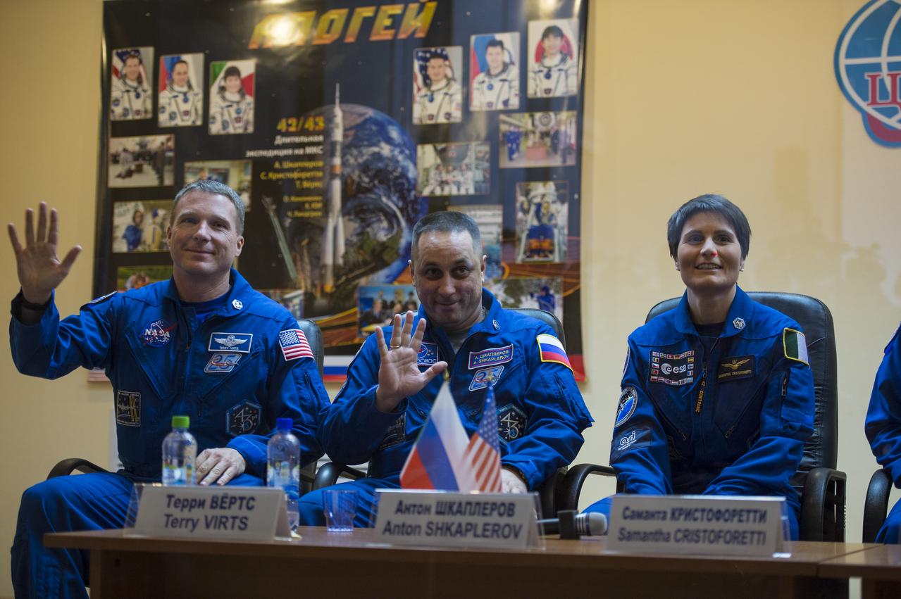 Expedition 42 Flight Engineer Terry Virts of NASA (left), Soyuz Commander Anton Shkaplerov of the Russian Federal Space Agency (Roscosmos) (center), and Flight Engineer Samantha Cristoforetti (right) of the European Space Agency , wave as they are introduced during a press conference, Saturday, Nov. 22, 2014, at the Cosmonaut Hotel in Baikonur, Kazakhstan. The mission to the International Space Station is set to launch Nov. 24 from the Baikonur Cosmodrome. Photo Credit: (NASA/Aubrey Gemignani)