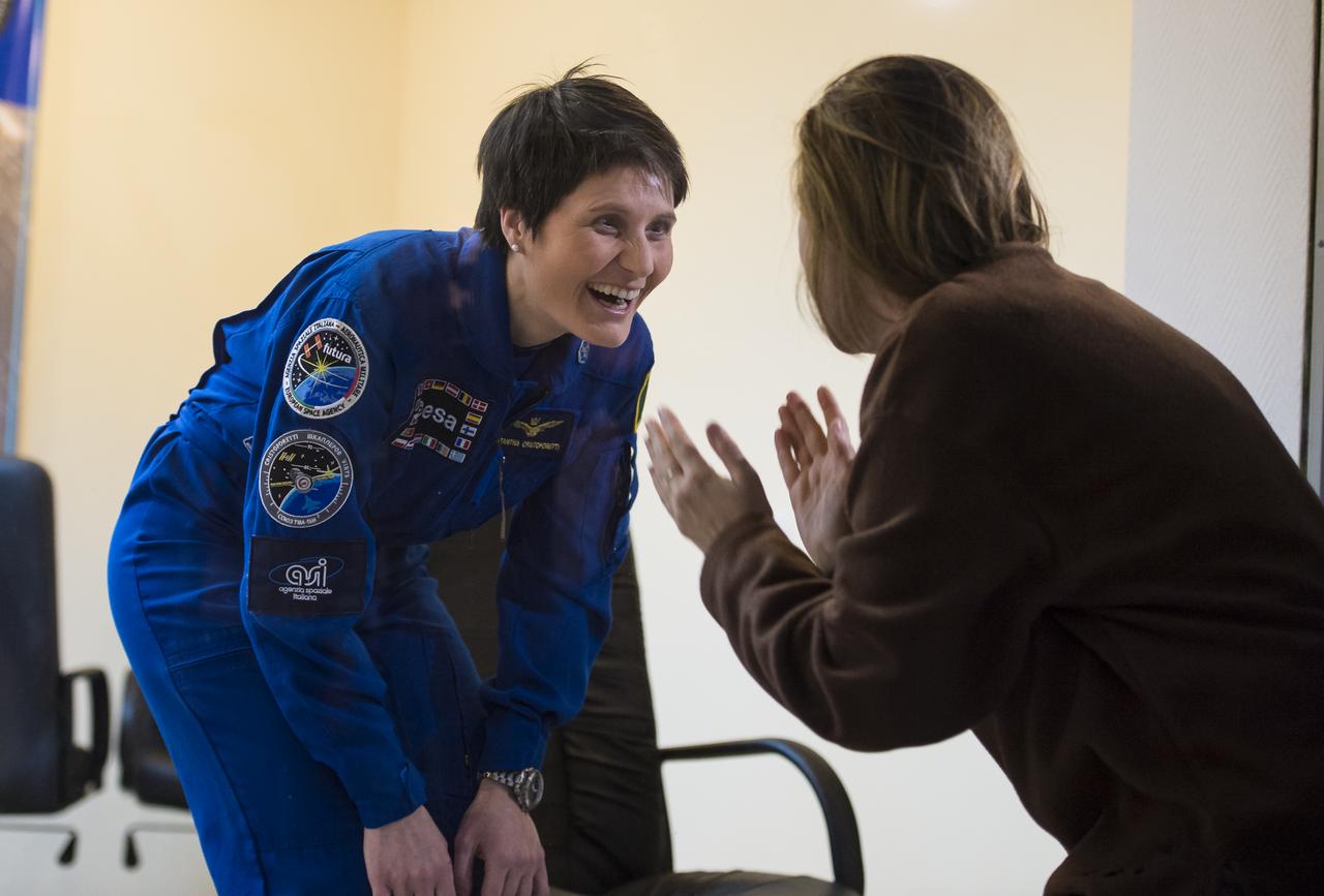 Flight Engineer Samantha Cristoforetti of the European Space Agency (ESA) speaks with friends and family through glass at the conclusion of the press conference, Saturday, Nov. 22, 2014, at the Cosmonaut Hotel in Baikonur, Kazakhstan. Launch of the Soyuz rocket is scheduled for Nov. 24 and will carry Cristoforetti, Flight Engineer Terry Virts of NASA , and Soyuz Commander Anton Shkaplerov of the Russian Federal Space Agency (Roscosmos) into orbit to begin their five and a half month mission on the International Space Station. Photo Credit: (NASA/Aubrey Gemignani)