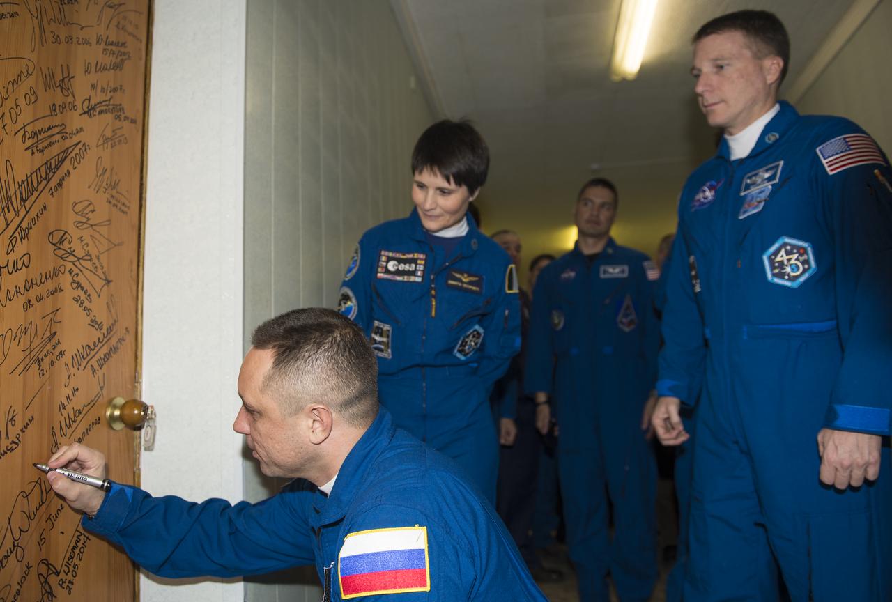 Expedition 42 Soyuz Commander Anton Shkaplerov of the Russian Federal Space Agency (Roscosmos) performs the traditional door signing at the Cosmonaut Hotel prior to departing the hotel for launch in a Soyuz rocket with fellow crewmates, Flight Engineers Samantha Cristoforetti of the European Space Agency (ESA) and Terry Virts of NASA, Sunday, Nov. 23, 2014 in Baikonur, Kazakhstan. Launch of the Soyuz rocket is scheduled for the early hours of Nov. 24 Kazakhstan time and will carry Shkaplerov, Cristoforetti, and Virts into orbit to begin their five and a half month mission on the International Space Station. Photo Credit (NASA/Aubrey Gemignani)