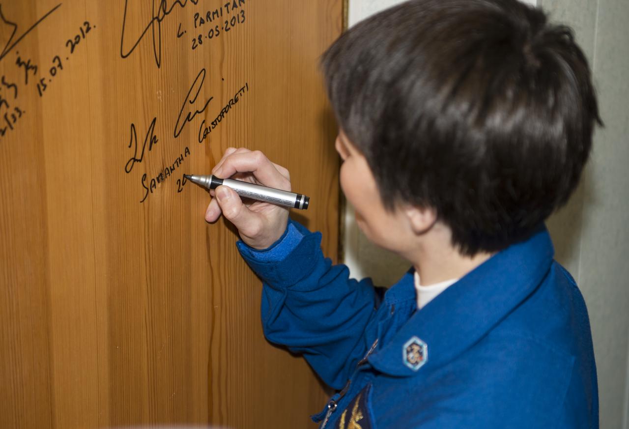 Expedition 42 Flight Engineer Samantha Cristoforetti of the European Space Agency (ESA), performs the traditional door signing at the Cosmonaut Hotel prior to departing the hotel for launch in a Soyuz rocket with fellow crewmates, Soyuz Commander Anton Shkaplerov of the Russian Federal Space Agency (Roscosmos) and Flight Engineer Terry Virts of NASA, Sunday, Nov. 23, 2014 in Baikonur, Kazakhstan. Launch of the Soyuz rocket is scheduled for the early hours of Nov. 24 Kazakhstan time and will carry Cristoforetti, Virts, and Shkaplerov into orbit to begin their five and a half month mission on the International Space Station. Photo Credit (NASA/Aubrey Gemignani)
