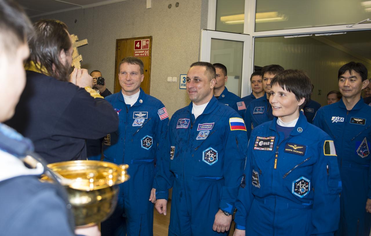 Expedition 42 Flight Engineer Terry Virts of NASA, left, Soyuz Commander Anton Shkaplerov of the Russian Federal Space Agency (Roscosmos), center, and Flight Engineer Samantha Cristoforetti of the European Space Agency (ESA), right, receive the traditional blessing from a Russian Orthodox priest at the Cosmonaut Hotel prior to their launch on the Soyuz rocket to the International Space Station (ISS), Sunday, Nov. 23, 2014, in Baikonur, Kazakhstan. Virts, Shkaplerov, and Cristoforetti will spend the next five and a half months living and working aboard the ISS. Photo Credit: (NASA/Aubrey Gemignani)