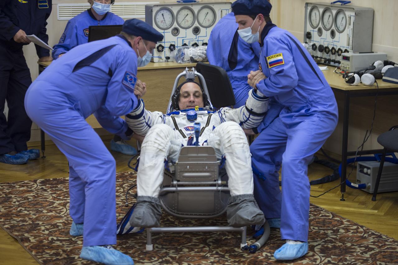 Expedition 42 Soyuz Commander Anton Shkaplerov of the Russian Federal Space Agency (Roscosmos) is helped up after having his Russian Sokol suit pressure checked in preparation for his launch aboard the Soyuz TMA-15M spacecraft on Sunday, Nov. 23, 2014, at the Baikonur Cosmodrome in Baikonur, Kazakhstan. Launch of the Soyuz rocket is scheduled for the early hours of Nov. 24 and will carry Shkaplerov and fellow crewmates, Flight Engineers Terry Virts of NASA and Samantha Cristoforetti of the European Space Agency (ESA) into orbit to begin their five and a half month mission on the International Space Station. Photo Credit: (NASA/Aubrey Gemignani)