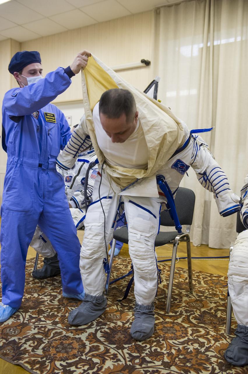 Expedition 42 Soyuz Commander Anton Shkaplerov of the Russian Federal Space Agency (Roscosmos) is helped into his Russian Sokol suit as he and fellow crewmates, Flight Engineer Samantha Cristoforetti of the European Space Agency (ESA), and Flight Engineer Terry Virts of NASA  prepare for their Soyuz launch to the International Space Station, on Sunday, Nov. 23, 2014, at the Baikonur Cosmodrome in Baikonur, Kazakhstan. Launch of the Soyuz rocket is scheduled for the early hours of Nov. 24 and will carry Shkaplerov, Virts, and Cristoforetti into orbit to begin their five and a half month mission on the International Space Station. Photo Credit: (NASAGCTC/Andrey Shelepin)