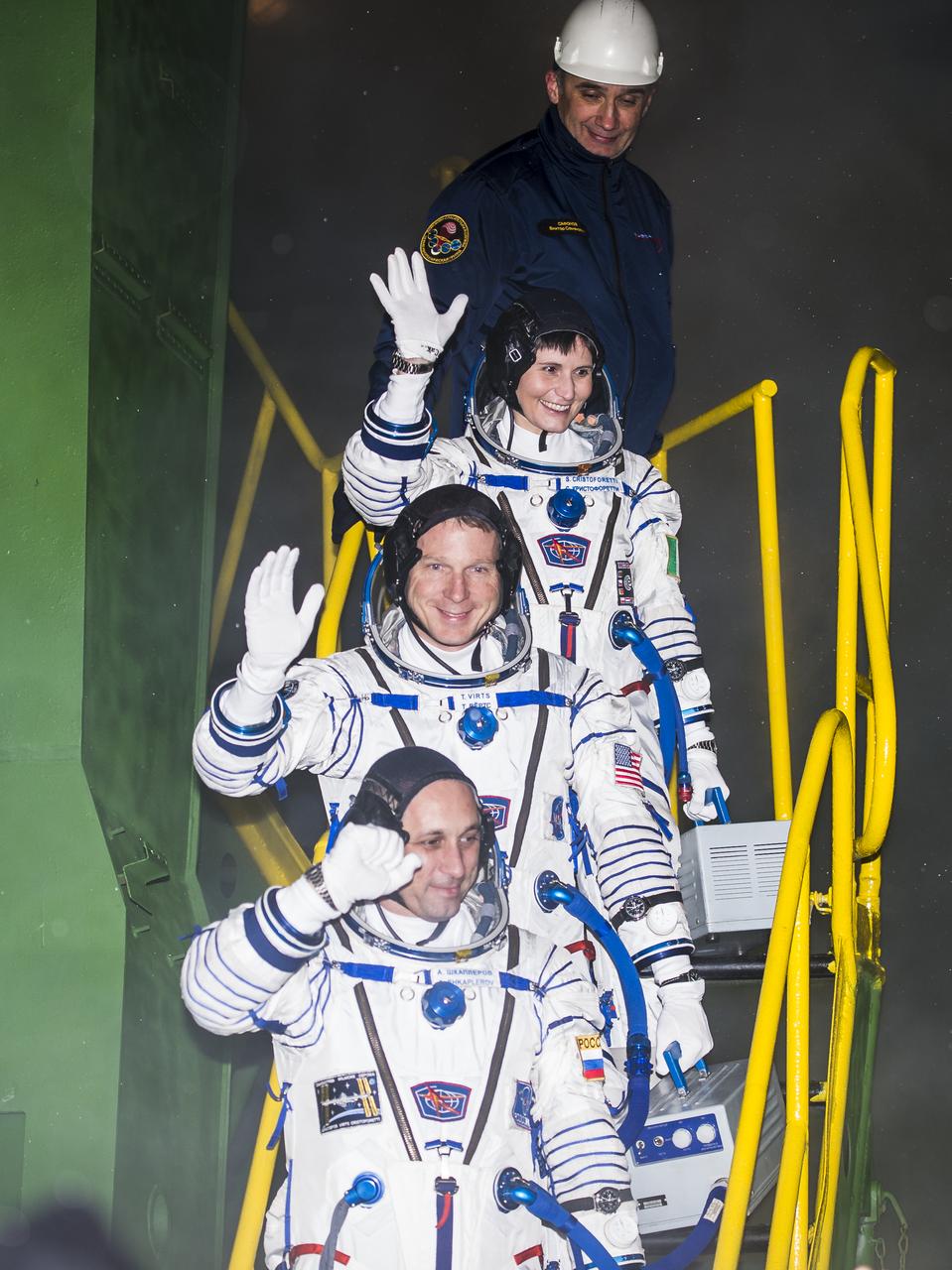 Expedition 42 Flight Engineer Samantha Cristoforetti, of the European Space Agency (ESA), top, Flight Engineer Terry Virts of NASA, center, and Soyuz Commander Anton Shkaplerov of the Russian Federal Space Agency (Roscosmos), bottom, wave farewell prior to boarding the Soyuz TMA-15M spacecraft for launch, Monday, Nov. 24, 2014 at the Baikonur Cosmodrome in Kazakhstan. Cristoforetti, Virts, and Shkaplerov will spend the next five and a half months aboard the International Space Station. Photo Credit: (NASA/Aubrey Gemignani)