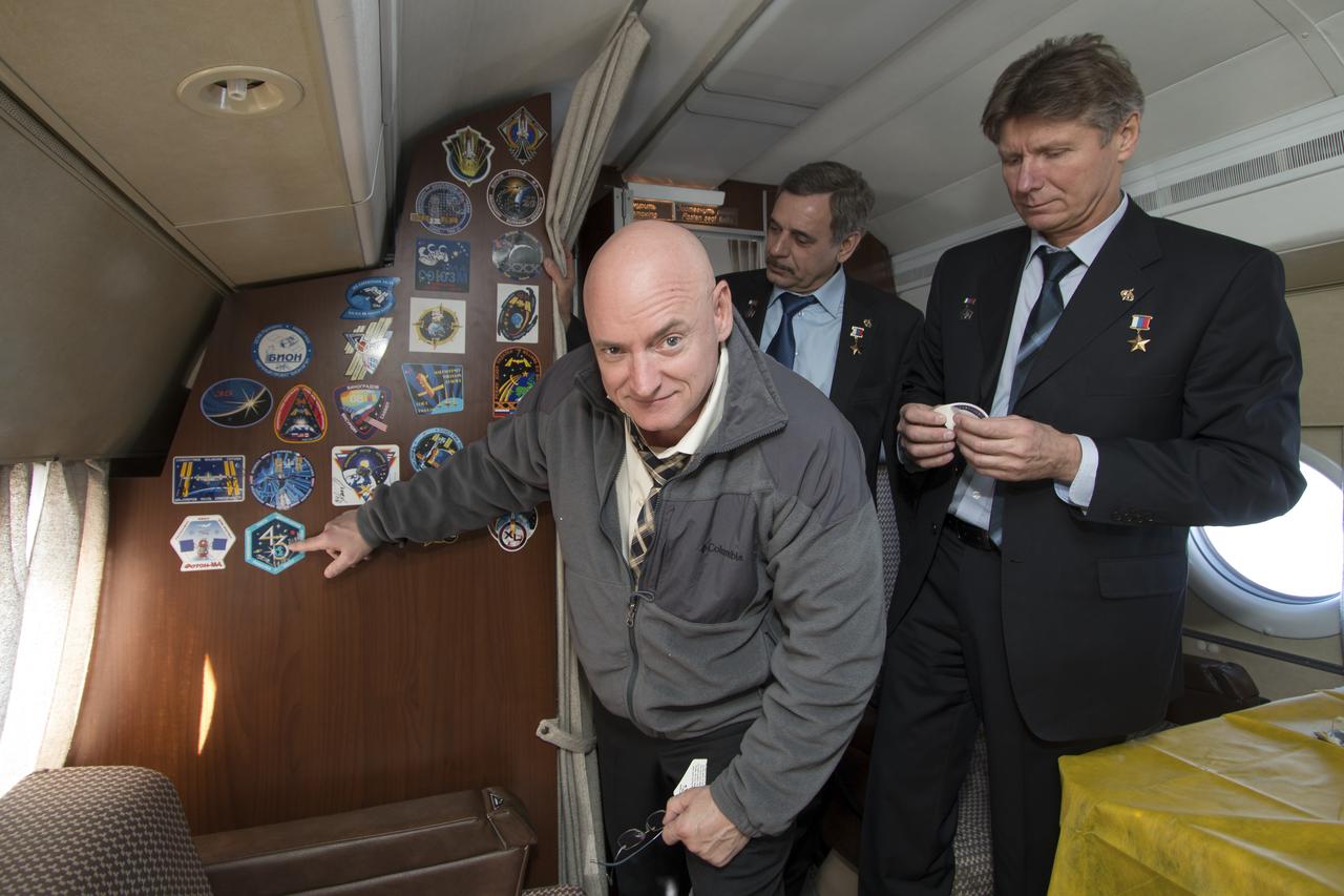 Expedition 43 NASA Astronaut Scott Kelly, points to his Expedition 43 crew mission patch after placing it on the  the Gagarin Cosmonaut Training Center (GCTC) aircraft during his flight from Star City, Russia, to Baikonur, Kazakhstan, with fellow crew members, Russian Cosmonauts Mikhail Kornienko, center, and Gennady Padalka of the Russian Federal Space Agency (Roscosmos), Saturday, March 14, 2015. The trio are preparing for launch to the International Space Station in their Soyuz TMA-16M spacecraft from the Baikonur Cosmodrome in Kazakhstan March 28, Kazakh time. As the one-year crew, Kelly and Kornienko will return to Earth on Soyuz TMA-18M in March 2016. Photo Credit: (NASA/Victor Zelentsov)