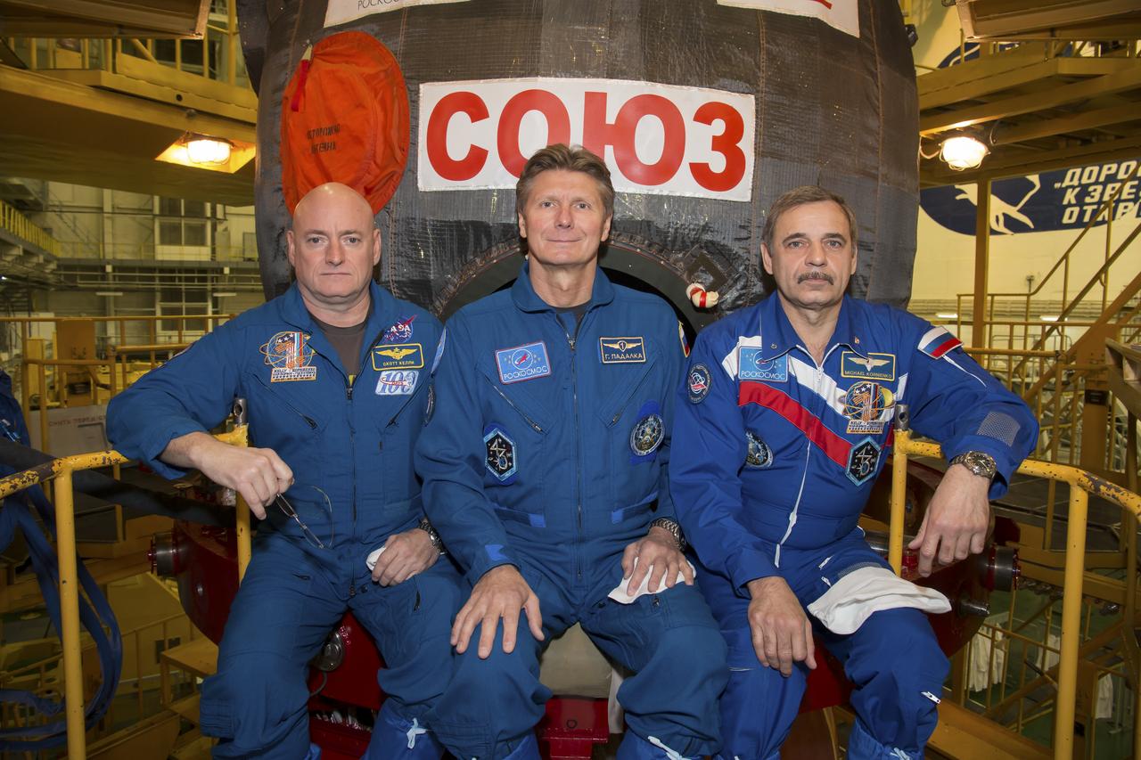 Expedition 43 NASA Astronaut Scott Kelly, left, and Russian Cosmonauts Gennady Padalka, center, and Mikhail Kornienko of the Russian Federal Space Agency (Roscosmos) take a moment during their Soyuz TMA-16M spacecraft fit check to pose for a photograph, Sunday, March 15, 2015 at the Baikonur Cosmodrome in Kazakhstan.  The trio are preparing for launch to the International Space Station in their Soyuz TMA-16M spacecraft from the Baikonur Cosmodrome in Kazakhstan March 28, Kazakh time. As the one-year crew, Kelly and Kornienko will return to Earth on Soyuz TMA-18M in March 2016. Photo Credit: (NASA/Victor Zelentsov)