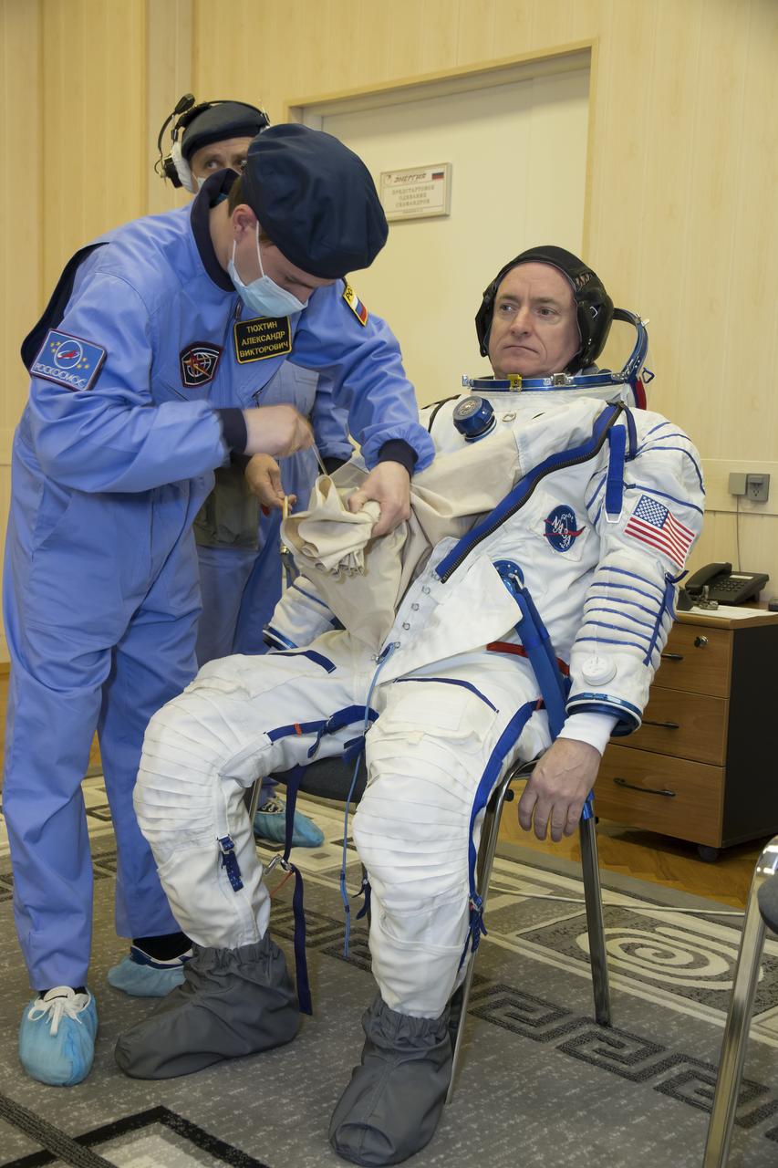 Expedition 43 NASA Astronaut Scott Kelly dons his Russian sokol suit during the Soyuz TMA-16M spacecraft fit check with Russian Cosmonauts Gennady Padalka and, Mikhail Kornienko of the Russian Federal Space Agency (Roscosmos), Sunday, March 15, 2015 at the Baikonur Cosmodrome in Kazakhstan. The trio are preparing for launch to the International Space Station in their Soyuz TMA-16M spacecraft from the Baikonur Cosmodrome in Kazakhstan March 28, Kazakh time. As the one-year crew, Kelly and Kornienko will return to Earth on Soyuz TMA-18M in March 2016. Photo Credit: (NASA/Victor Zelentsov)