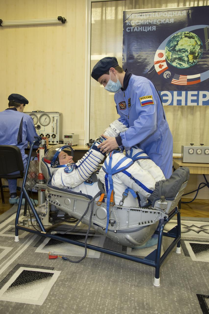 Expedition 43 NASA Astronaut Scott Kelly prepares to have his Russian sokol suit pressure checked during the Soyuz TMA-16M spacecraft fit check with Russian Cosmonauts Gennady Padalka and, Mikhail Kornienko of the Russian Federal Space Agency (Roscosmos), Sunday, March 15, 2015 at the Baikonur Cosmodrome in Kazakhstan. The trio are preparing for launch to the International Space Station in their Soyuz TMA-16M spacecraft from the Baikonur Cosmodrome in Kazakhstan March 28, Kazakh time. As the one-year crew, Kelly and Kornienko will return to Earth on Soyuz TMA-18M in March 2016. Photo Credit: (NASA/Victor Zelentsov)