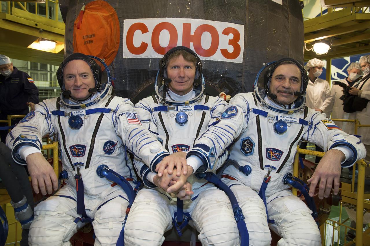 Expedition 43 NASA Astronaut Scott Kelly, left, and Russian Cosmonauts Gennady Padalka, center, and Mikhail Kornienko of the Russian Federal Space Agency (Roscosmos) take a moment during their Soyuz TMA-16M spacecraft fit check to pose for a photograph, Sunday, March 15, 2015 at the Baikonur Cosmodrome in Kazakhstan.  The trio are preparing for launch to the International Space Station in their Soyuz TMA-16M spacecraft from the Baikonur Cosmodrome in Kazakhstan March 28, Kazakh time. As the one-year crew, Kelly and Kornienko will return to Earth on Soyuz TMA-18M in March 2016. Photo Credit: (NASA/Victor Zelentsov)
