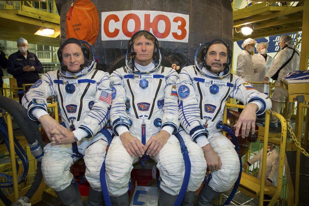 Expedition 43 NASA Astronaut Scott Kelly, left, and Russian Cosmonauts Gennady Padalka, center, and Mikhail Kornienko of the Russian Federal Space Agency (Roscosmos) take a moment during their Soyuz TMA-16M spacecraft fit check to pose for a photograph, Sunday, March 15, 2015 at the Baikonur Cosmodrome in Kazakhstan. The trio are preparing for launch to the International Space Station in their Soyuz TMA-16M spacecraft from the Baikonur Cosmodrome in Kazakhstan March 28, Kazakh time. As the one-year crew, Kelly and Kornienko will return to Earth on Soyuz TMA-18M in March 2016. Photo Credit: (NASA/Victor Zelentsov)