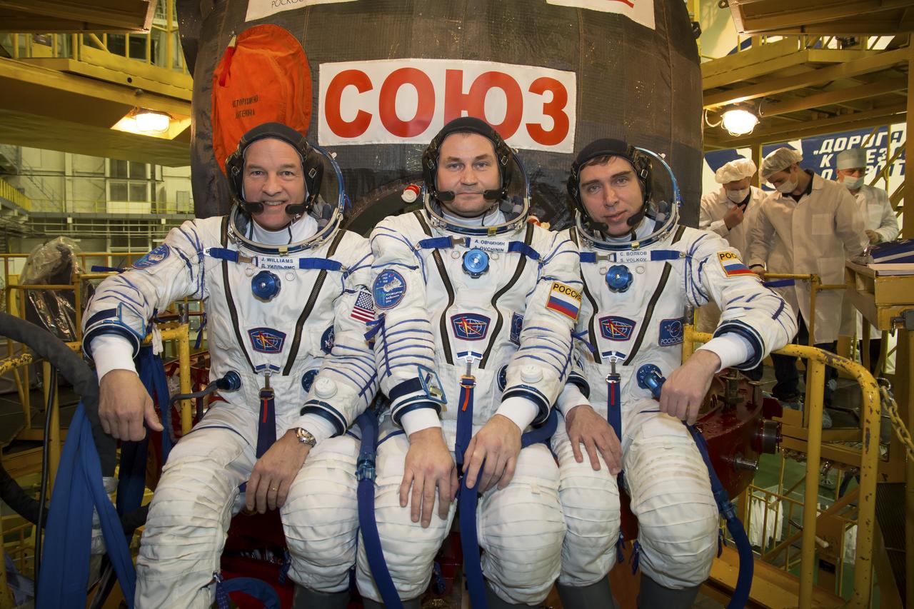 Expedition 43 backup crew members Jeff Williams of NASA, left, Alexey Ovchinin, center, and Sergei Volkov of Russia's Federal Space Agency (Roscosmos) take a moment during their Soyuz TMA-16M spacecraft fit check to pose for a photograph, Sunday, March 15, 2015 at the Baikonur Cosmodrome in Kazakhstan. The prime crew members Russian Cosmonauts Mikhail Kornienko, Gennady Padalka of the Russian Federal Space Agency (Roscosmos), and NASA Astronaut Scott Kelly are preparing for launch to the International Space Station in their Soyuz TMA-16M spacecraft from the Baikonur Cosmodrome in Kazakhstan March 28, Kazakh time. As the one-year crew, Kelly and Kornienko will return to Earth on Soyuz TMA-18M in March 2016. Photo Credit: (NASA/Victor Zelentsov)