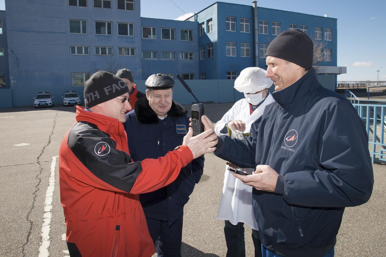 Expedition 43 NASA Astronaut Scott Kelly, left, and Russian Cosmonaut Gennady Padalka of the Russian Federal Space Agency (Roscosmos) take turns testing a satellite phone during their Soyuz TMA-16M spacecraft fit check with fellow crew member Mikhail Kornienko of Roscosmos, Sunday, March 15, 2015 at the Baikonur Cosmodrome in Kazakhstan. The trio are preparing for launch to the International Space Station in their Soyuz TMA-16M spacecraft from the Baikonur Cosmodrome in Kazakhstan March 28, Kazakh time. As the one-year crew, Kelly and Kornienko will return to Earth on Soyuz TMA-18M in March 2016. Photo Credit: (NASA/Victor Zelentsov)