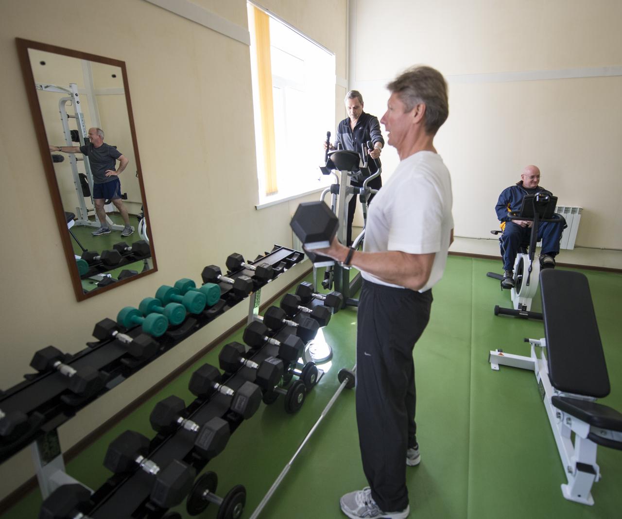 Expedition 43 backup crew member NASA Astronaut Jeff Williams, reflected in mirror, Russian Cosmonauts Mikhail Kornienko, on elliptical, Gennady Padalka of the Russian Federal Space Agency (Roscosmos), and NASA Astronaut Scott Kelly, right, are seen exercising during media day, Saturday, March 21, 2015, Baikonur, Kazakhstan. Padalka, Kornienko, and Kelly are scheduled to launch to the International Space Station in the Soyuz TMA-16M spacecraft from the Baikonur Cosmodrome in Kazakhstan March 28, Kazakh time (March 27 Eastern time.) As the one-year crew, Kelly and Kornienko will return to Earth on Soyuz TMA-18M in March 2016. Photo Credit: (NASA/Bill Ingalls)