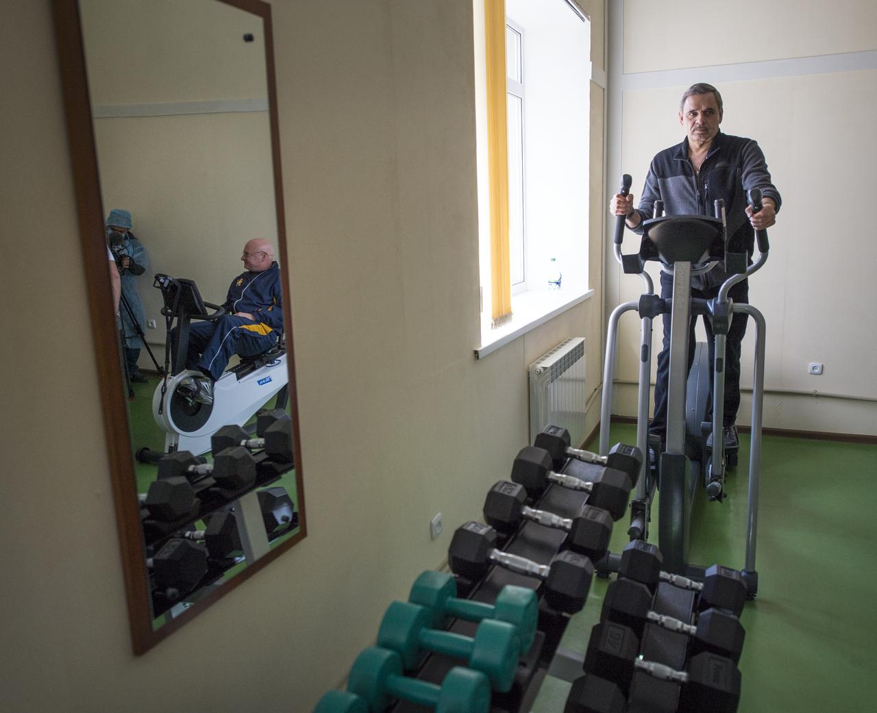 Expedition 43 NASA Astronaut Scott Kelly, left in mirror, and Russian Cosmonaut Mikhail Kornienko, of the Russian Federal Space Agency (Roscosmos) are seen exercising during media day, Saturday, March 21, 2015, Baikonur, Kazakhstan. Kornienko, Kelly and Russian Cosmonaut Gennady Padalka of Roscosmos are scheduled to launch to the International Space Station in the Soyuz TMA-16M spacecraft from the Baikonur Cosmodrome in Kazakhstan March 28, Kazakh time (March 27 Eastern time.) As the one-year crew, Kelly and Kornienko will return to Earth on Soyuz TMA-18M in March 2016. Photo Credit: (NASA/Bill Ingall