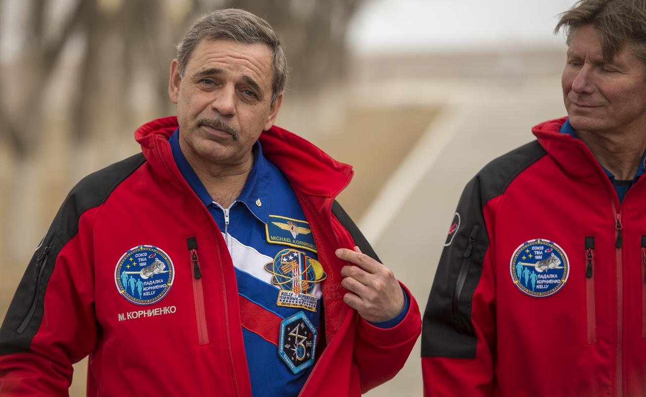 Expedition 43 Russian Cosmonaut Mikhail Kornienko of the Russian Federal Space Agency (Roscosmos), left, shows his One-Year and Expedition 43 mission patches to members of the press during media day, Saturday, March 21, 2015 at the Cosmonaut Hotel in Baikonur, Kazakhstan. Kornienko, NASA Astronaut Scott Kelly, and Russian Cosmonaut Gennady Padalka of Roscosmos are scheduled to launch to the International Space Station in the Soyuz TMA-16M spacecraft from the Baikonur Cosmodrome in Kazakhstan March 28, Kazakh time (March 27 Eastern time.) As the one-year crew, Kelly and Kornienko will return to Earth on Soyuz TMA-18M in March 2016. Photo Credit: (NASA/Bill Ingalls)