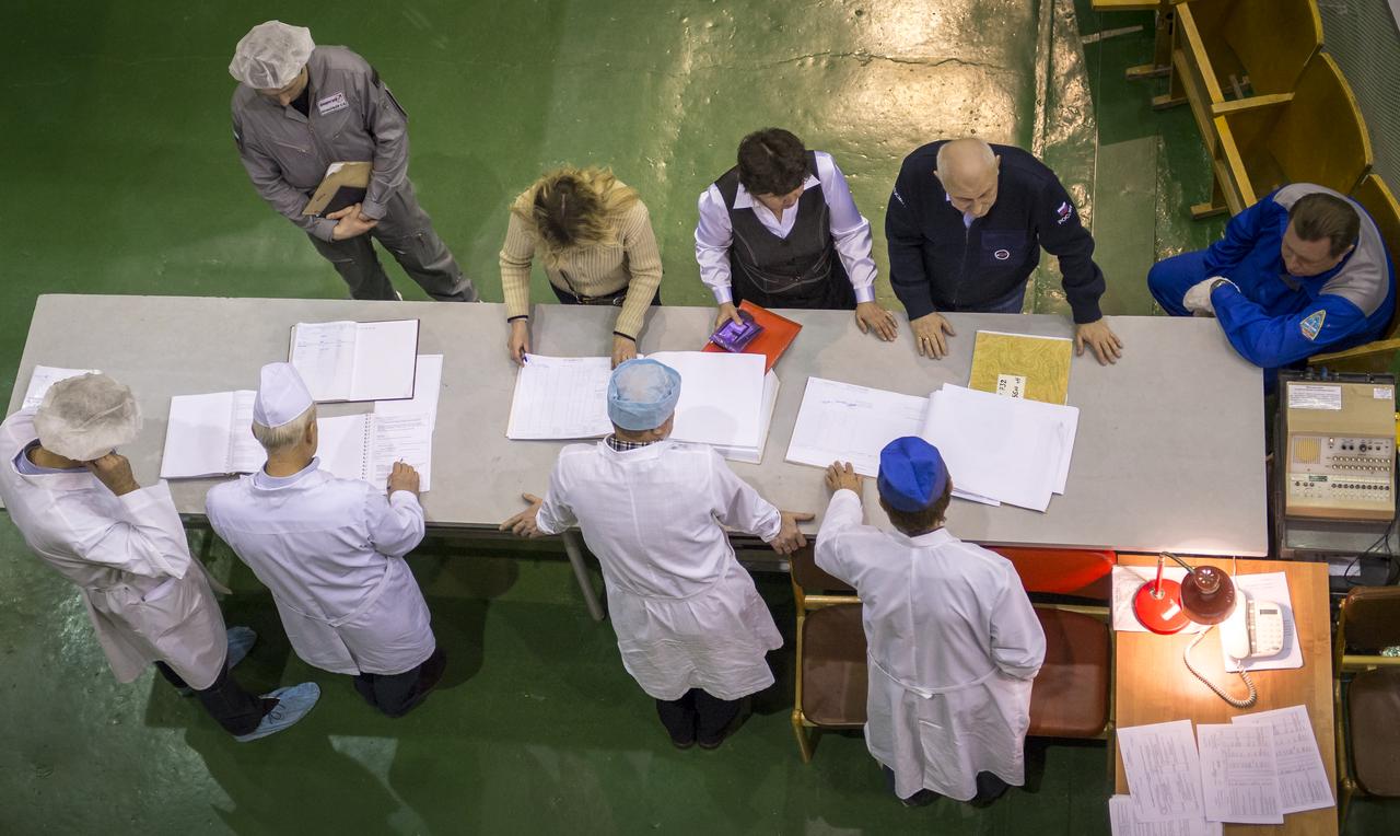 Support personnel review and sign workflow documents at the base of the Soyuz TMA-16M spacecraft during the final check of the spacecraft, Monday, March 23, 2015 at the Baikonur Cosmodrome in Kazakhstan. NASA Astronaut Scott Kelly, and Russian Cosmonauts Mikhail Kornienko, and Gennady Padalka of the Russian Federal Space Agency (Roscosmos) are scheduled to launch to the International Space Station in the Soyuz TMA-16M spacecraft from the Baikonur Cosmodrome in Kazakhstan March 28, Kazakh time (March 27 Eastern time.) As the one-year crew, Kelly and Kornienko will return to Earth on Soyuz TMA-18M in March 2016. Photo Credit: (NASA/Bill Ingalls)